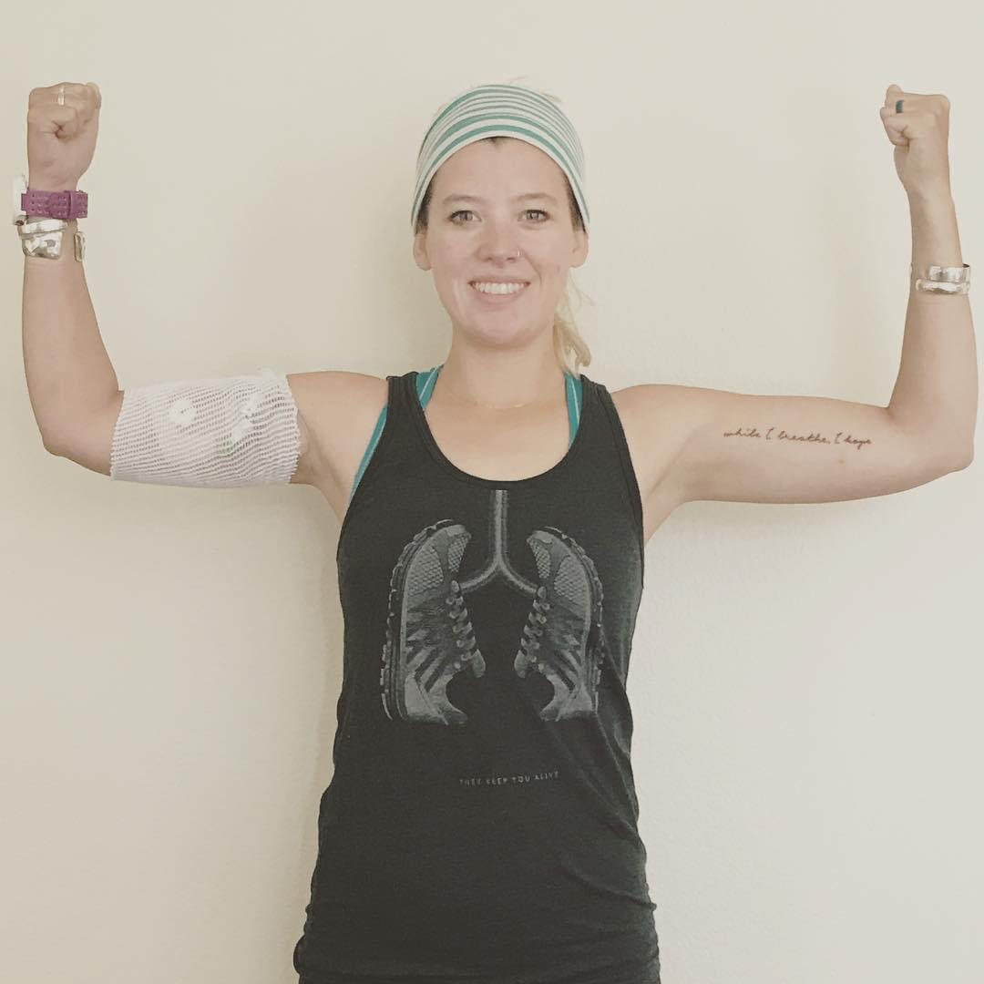 A photo of a woman flexing while wearing a tank top with a lungs design on it.