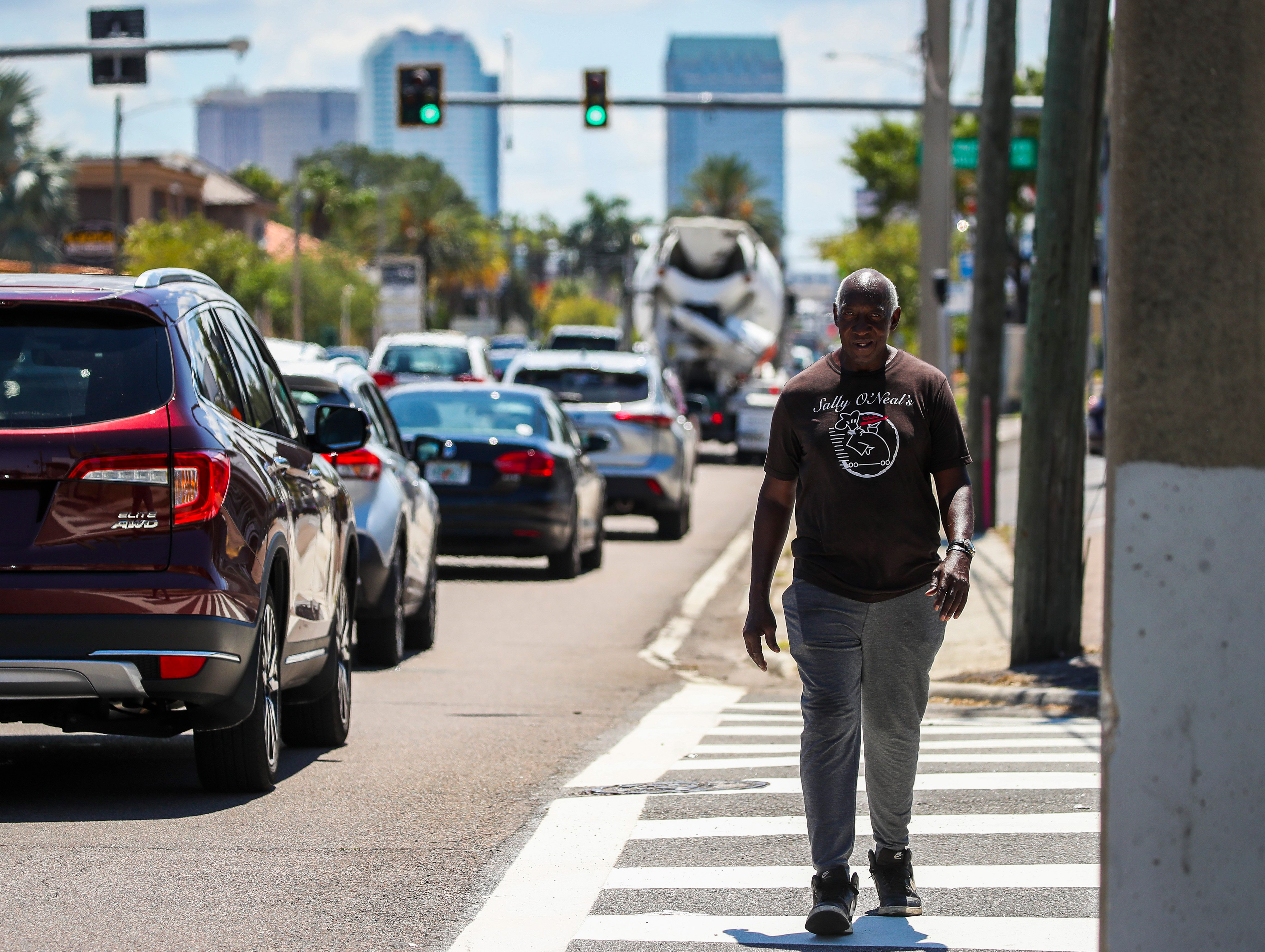 A photo of a man walking on the street in bright sunlight.