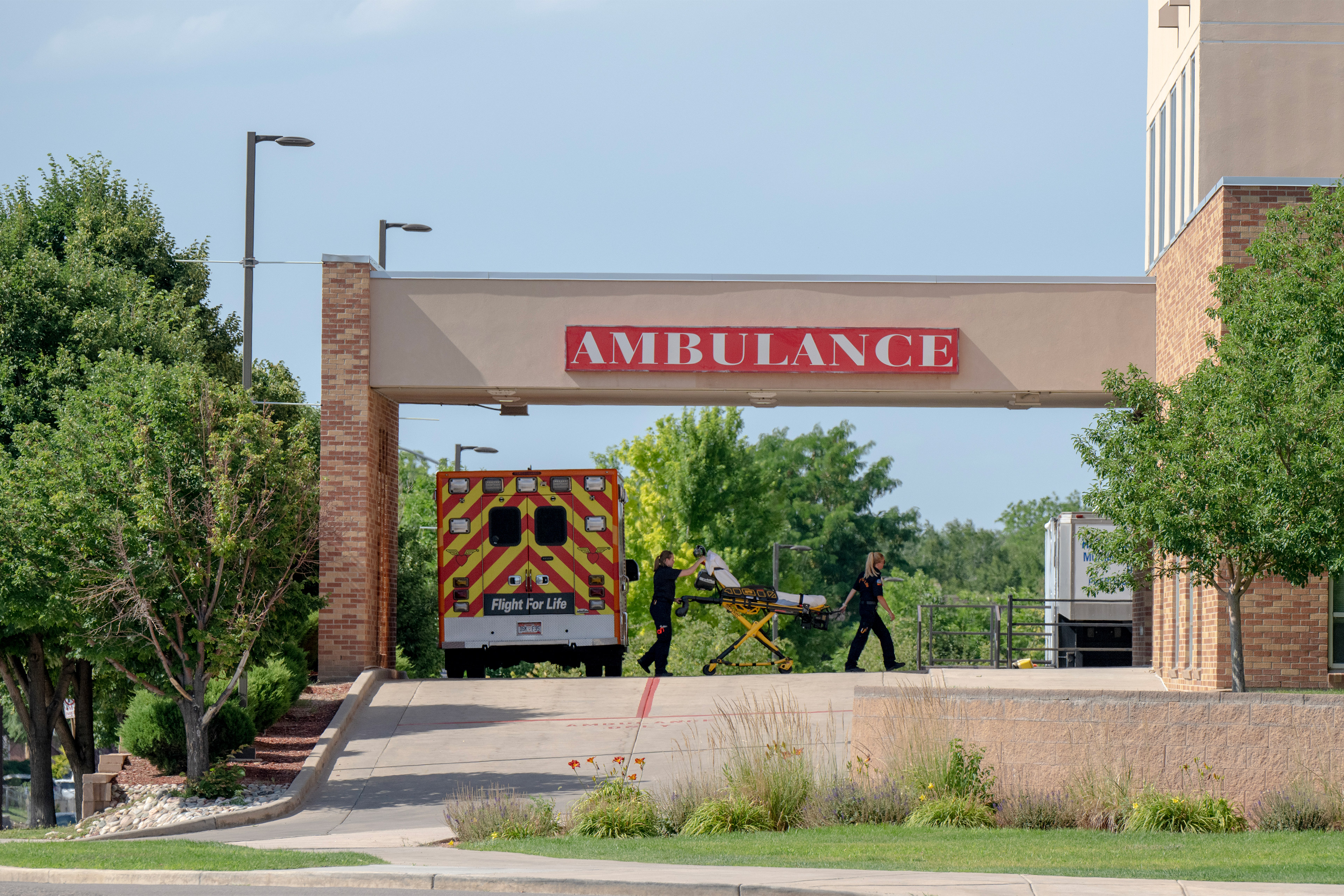 A photo of medical staff wheeling an empty stretcher into a hospital.