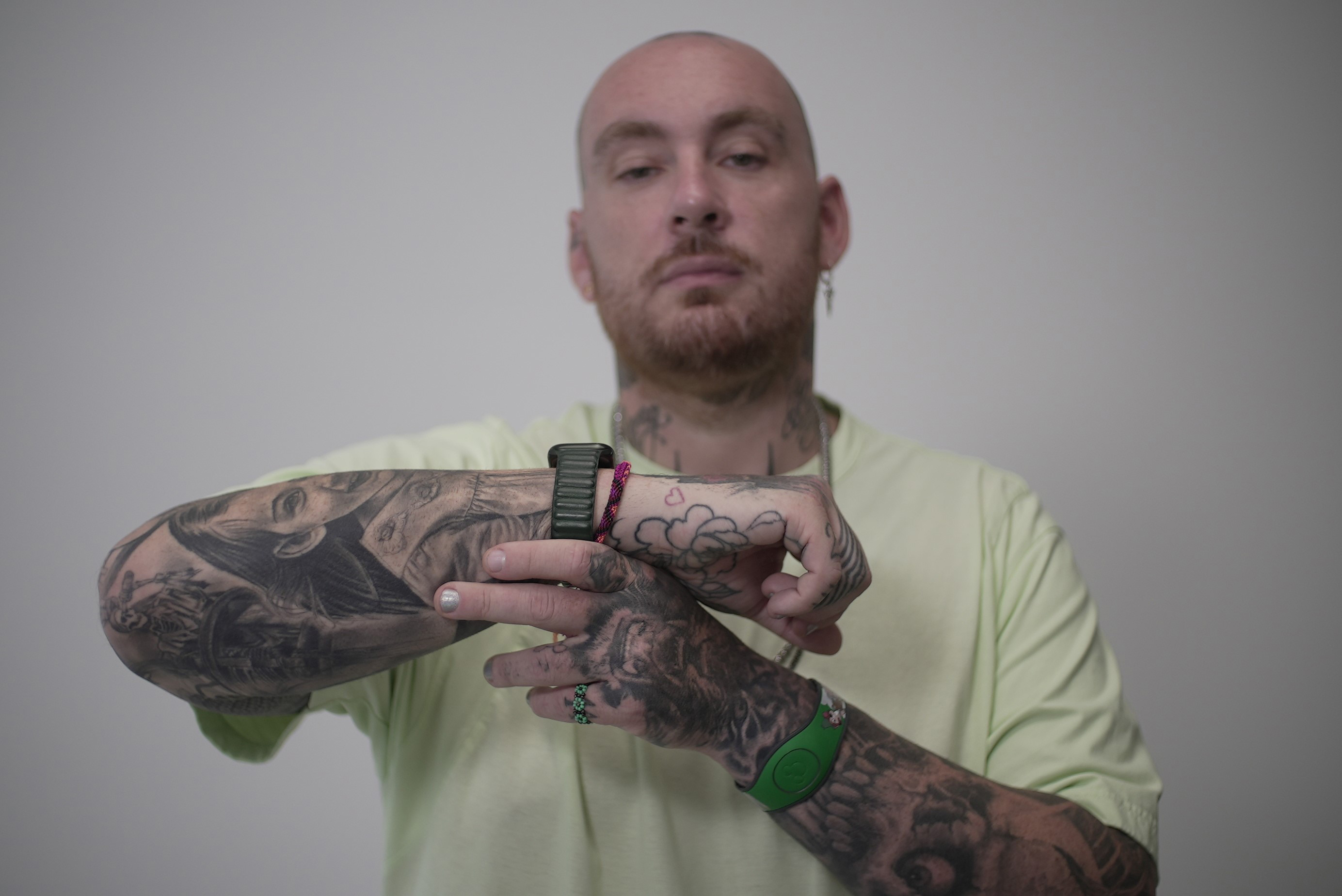 A photo of a man holding up the side of his hand to show a red heart tattoo.