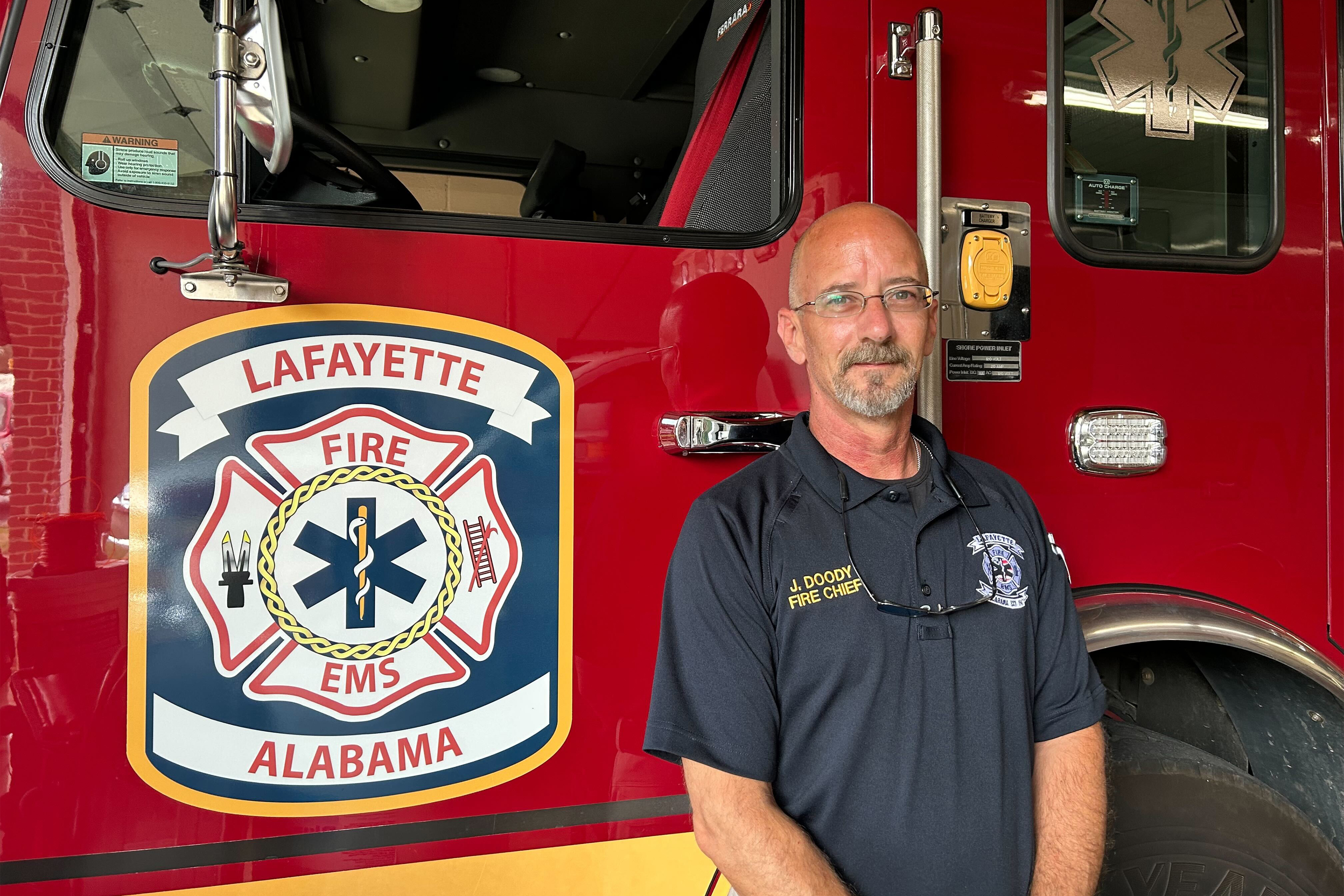 A photo of a man standing in front of a fire engine.