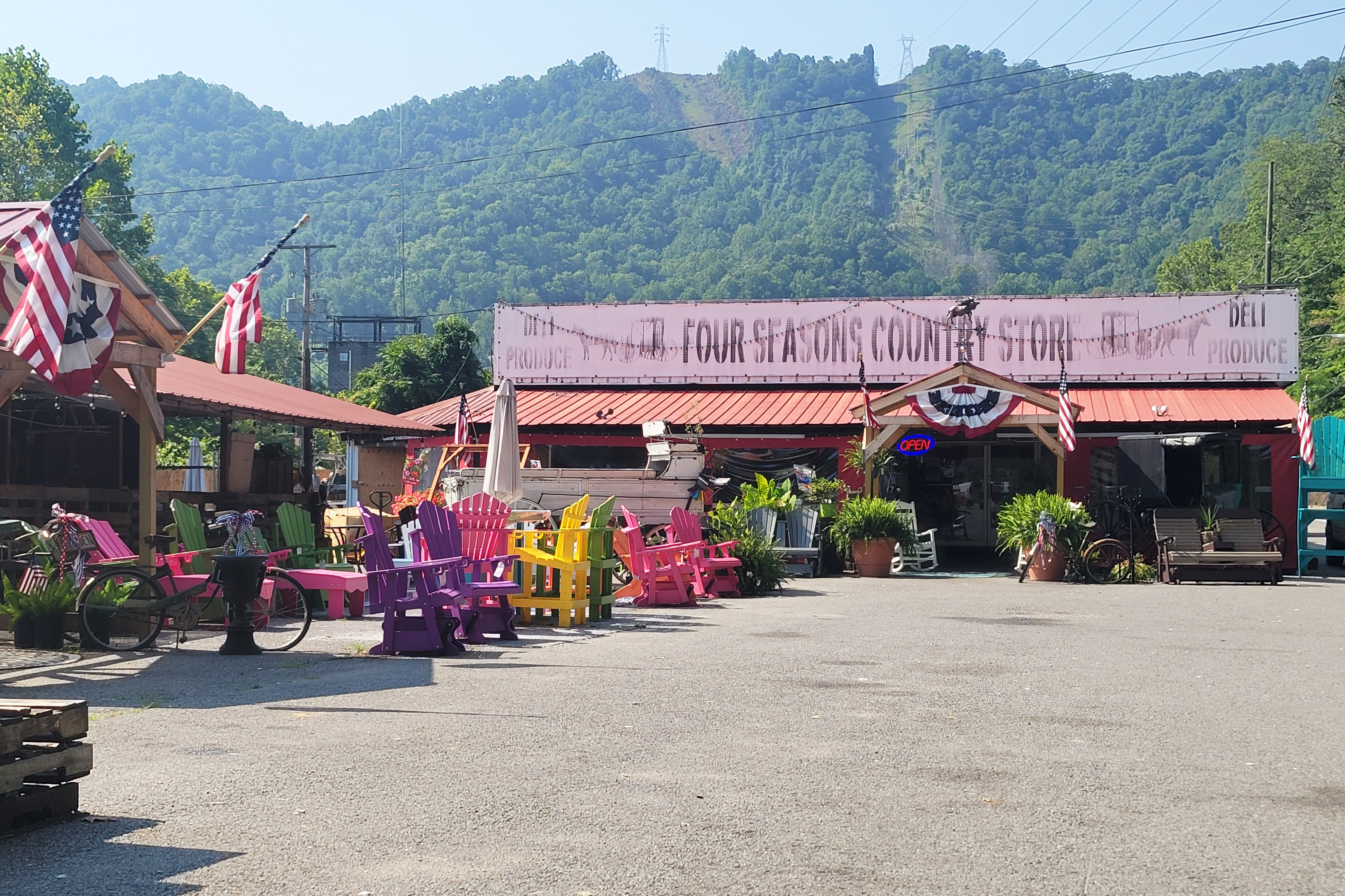 A photo of the exterior of a country store with colorful Adirondack chairs nestled in front of it.