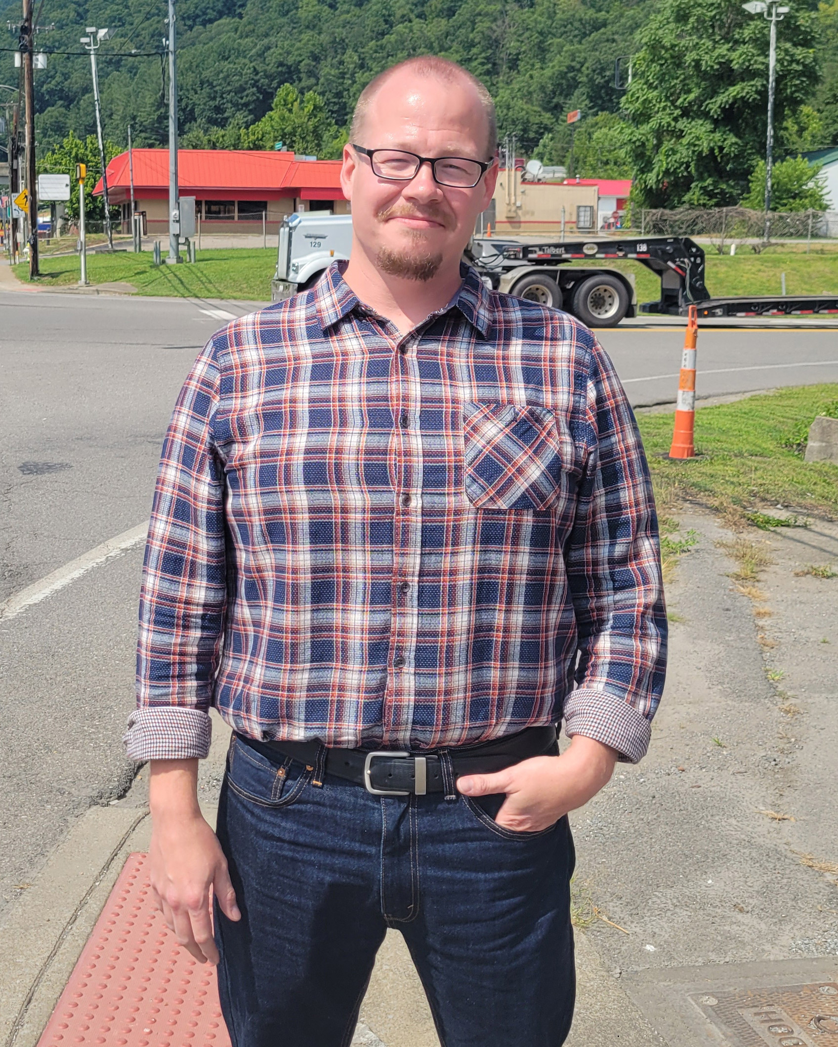 A photo of a man posing for a photo outside.