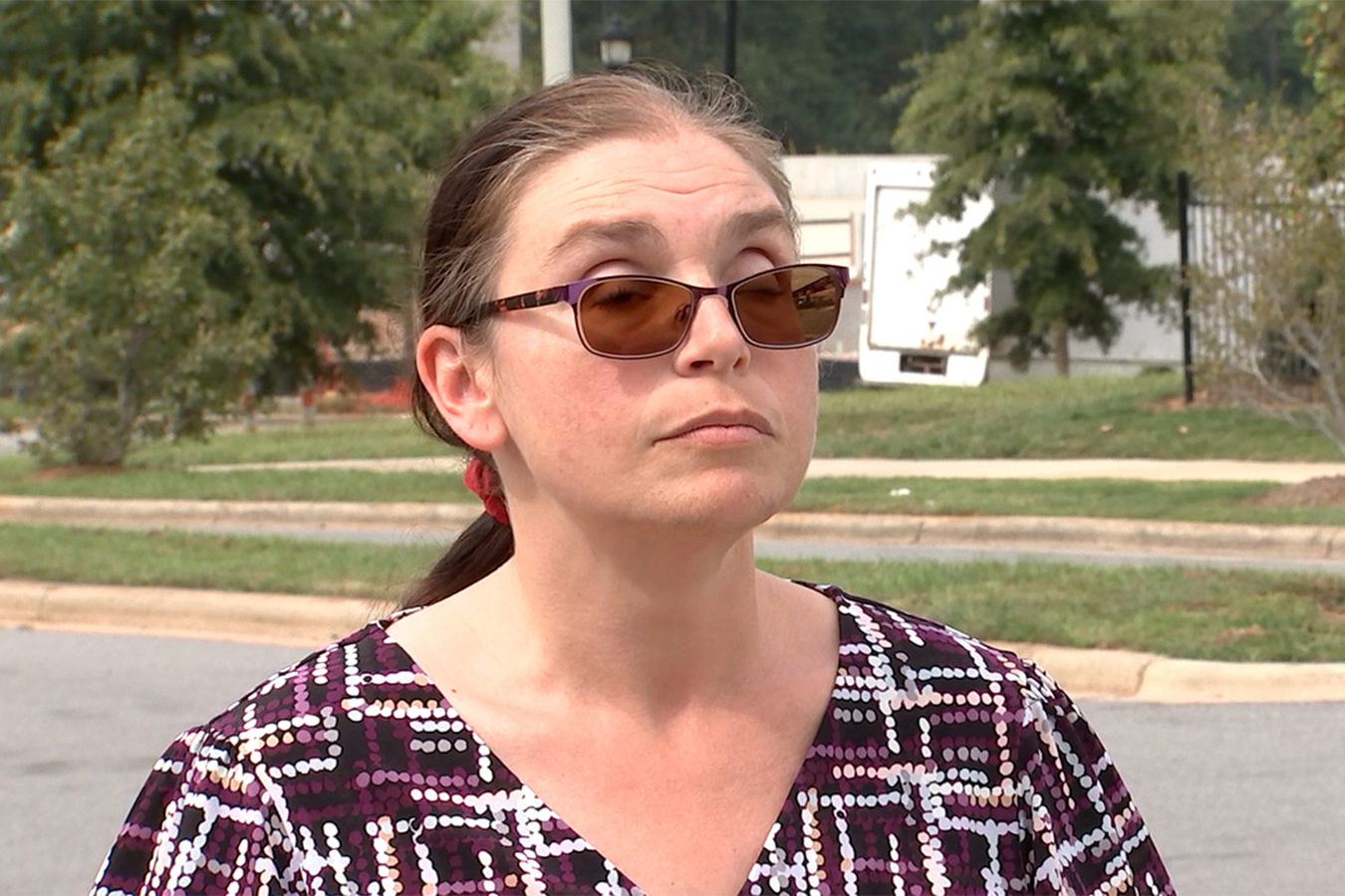 A photo of a blind woman standing outside.