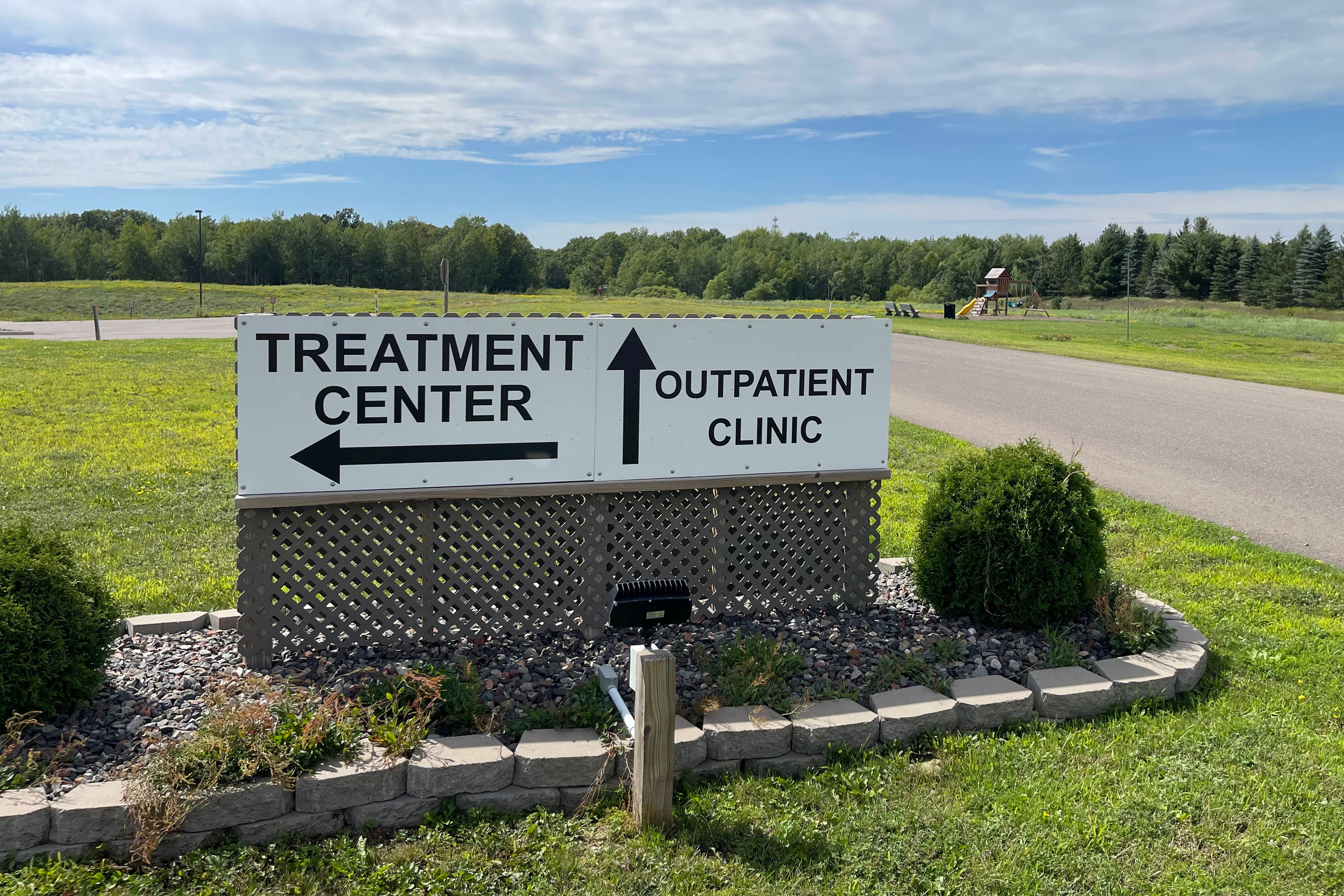 A photo of a sign directing traffic to a treatment center and an outpatient clinic.