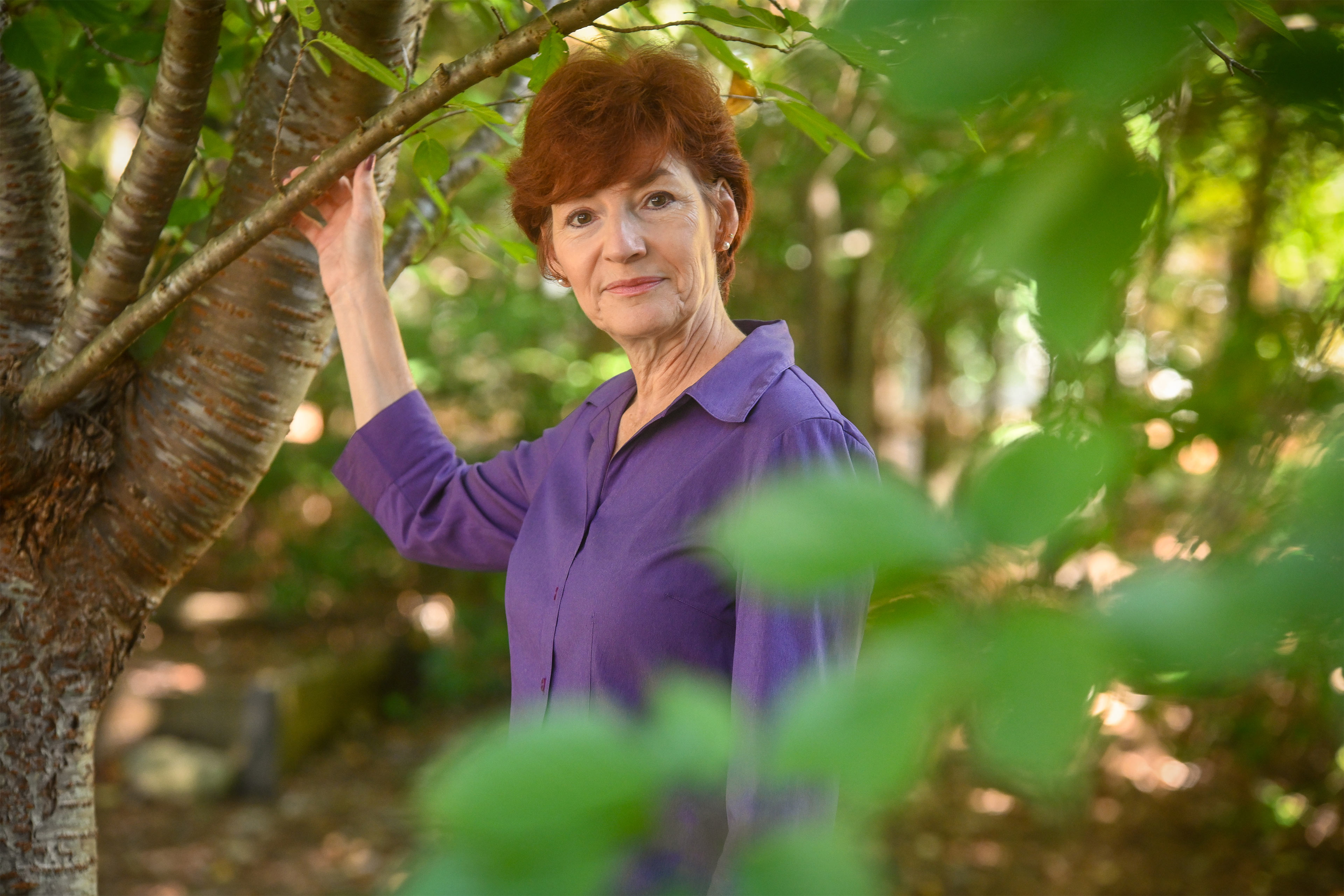 A photo of a woman posing for a portrait outside.