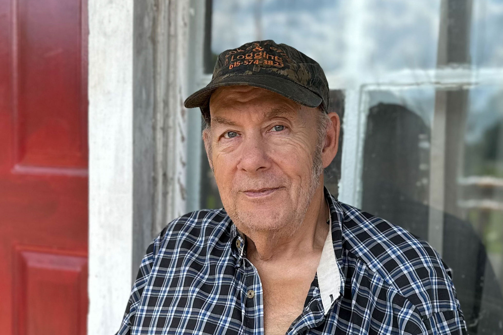 A photo of a man standing outside by a window.