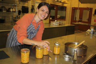 A photo of a woman smiling for the camera while canning hot sauce.