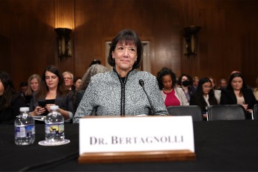A photo of Monica Bertagnolli sitting inside of a Senate committee room with her nameplate visible in front of her.