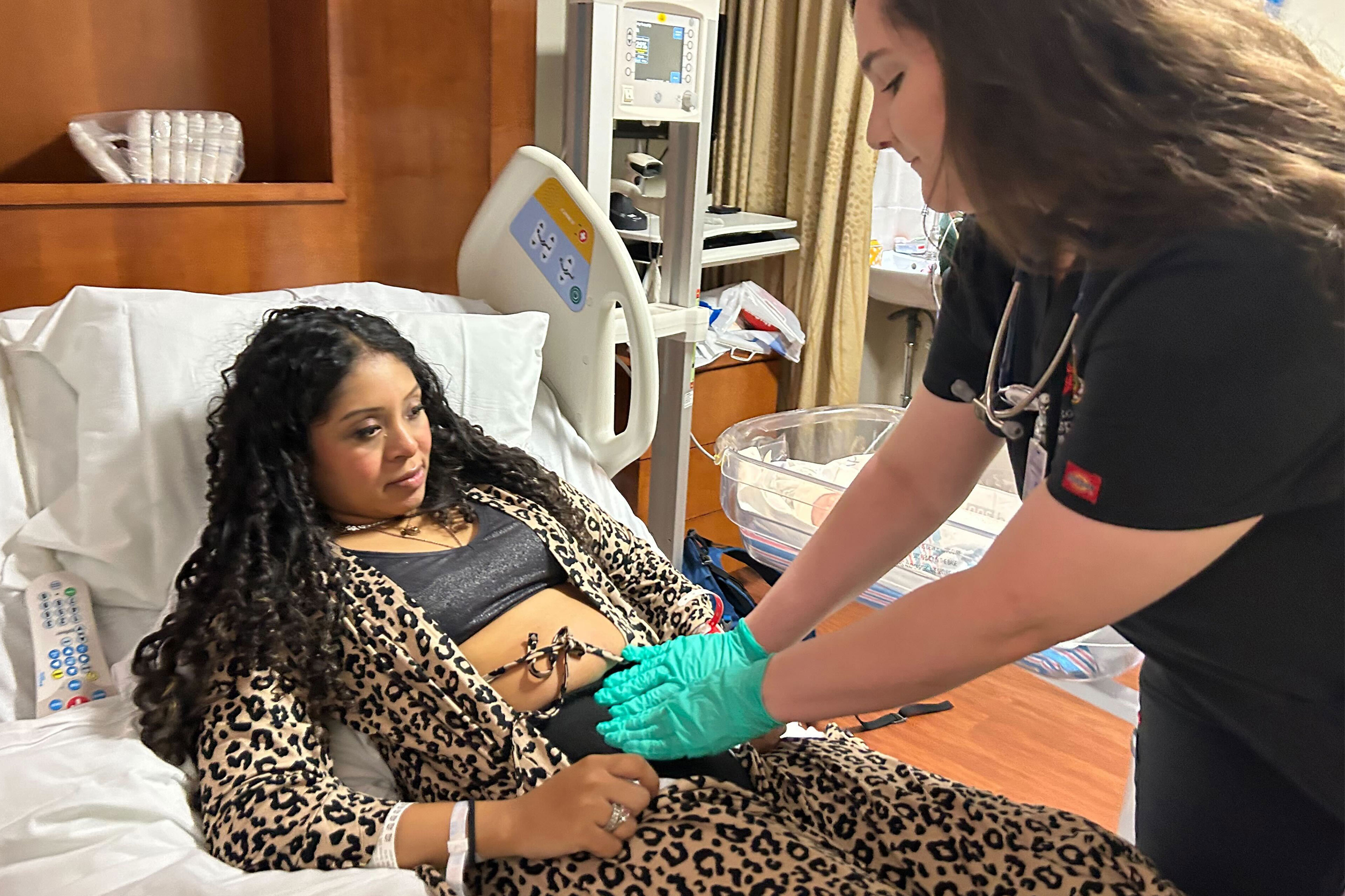 A photo of a medical student checking in on a mother after giving birth.