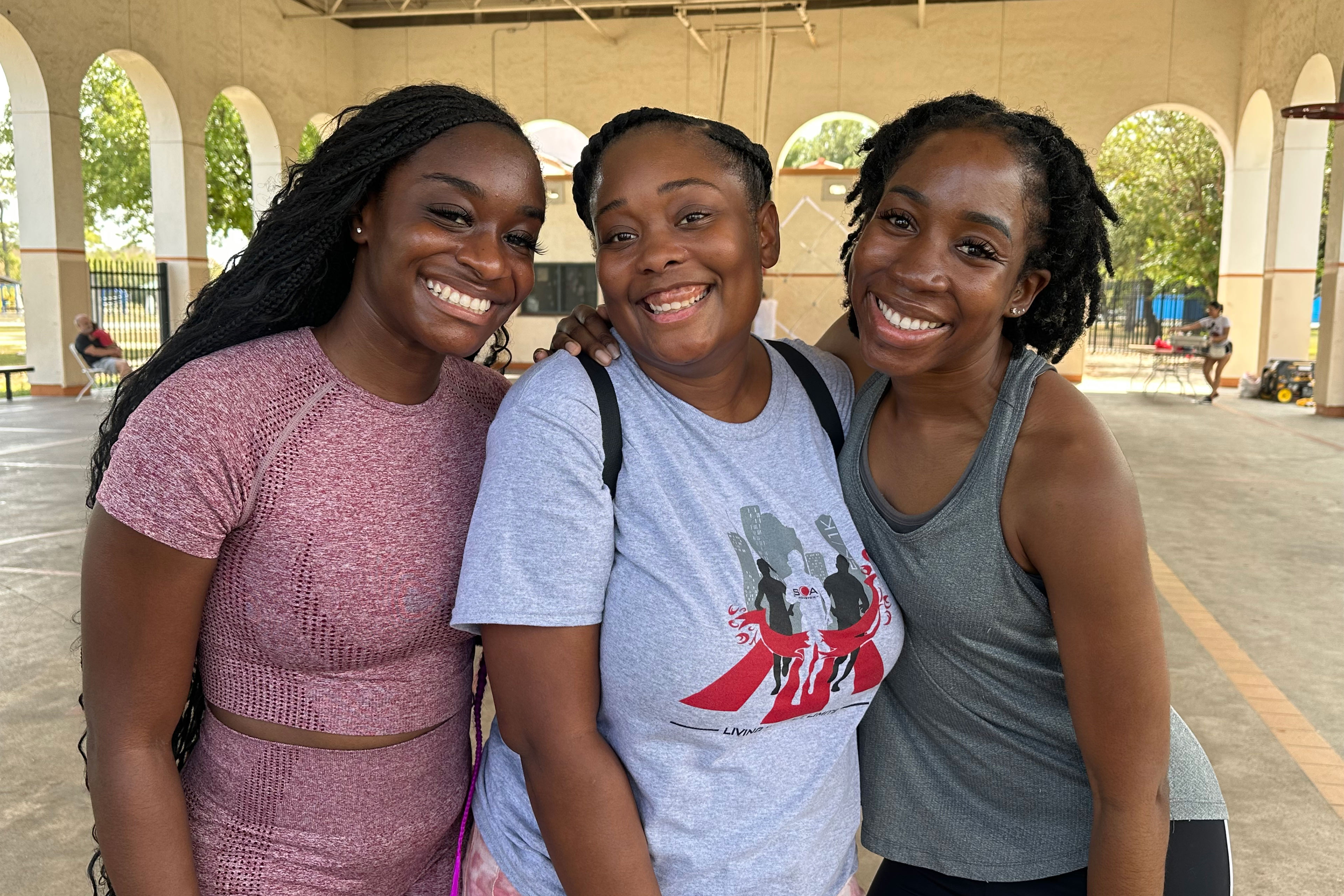 A photo of three Black women posing for a photo together outside.