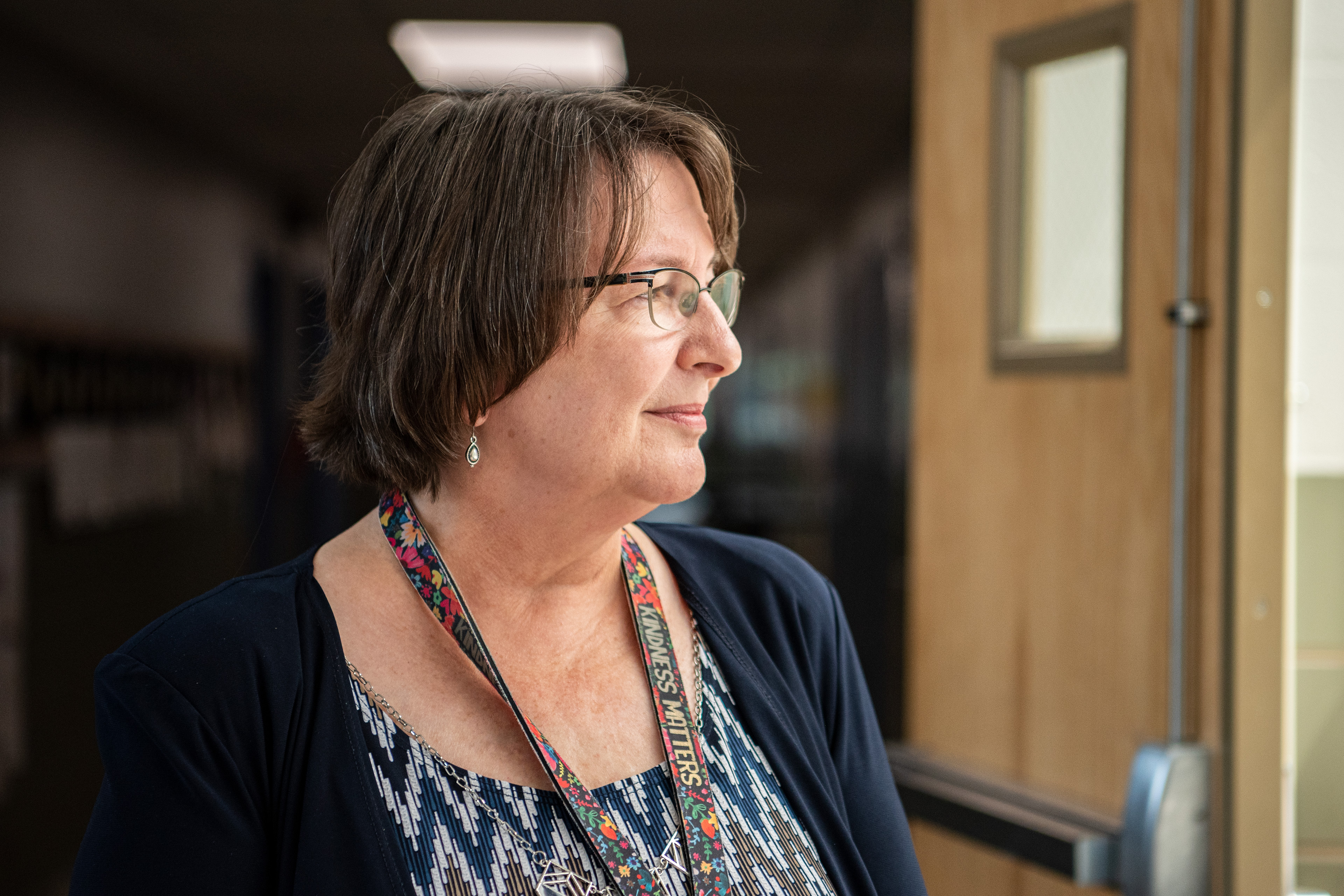 A photo of a woman looking out of window inside of a school.