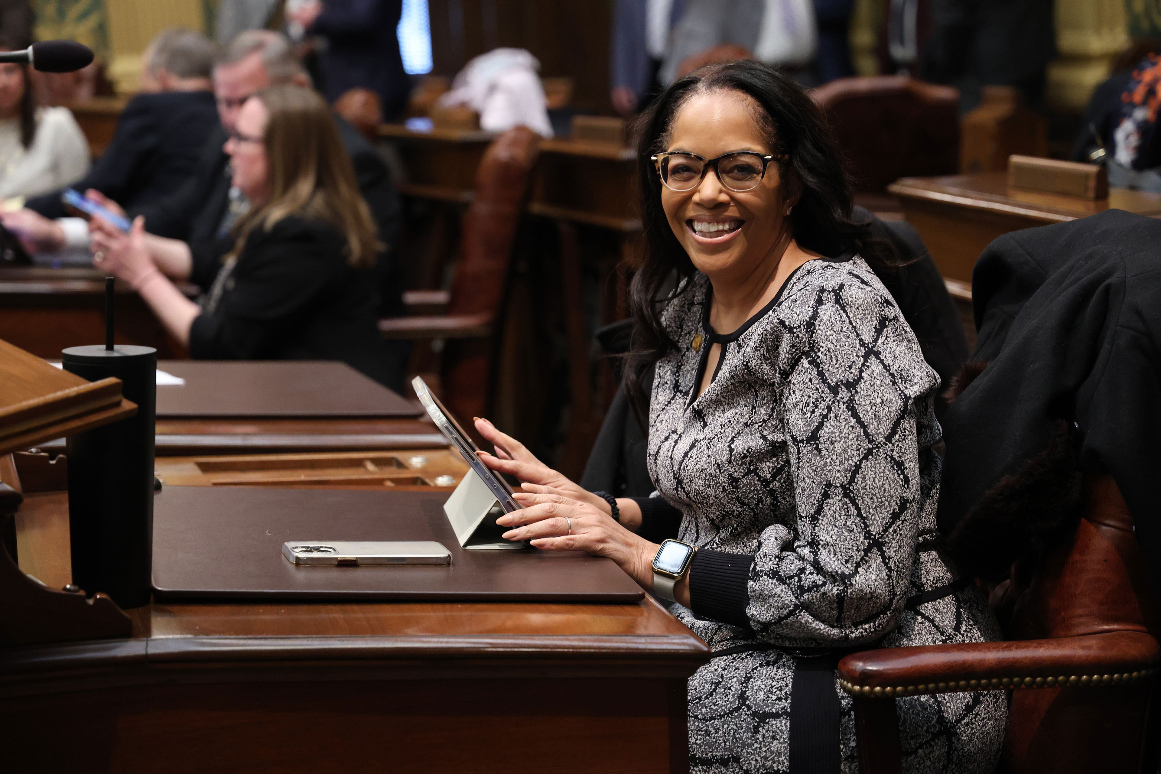 Uma foto da deputada de Michigan, Karen Whitsett, sorrindo para a câmera dentro da Câmara dos Representantes do estado.