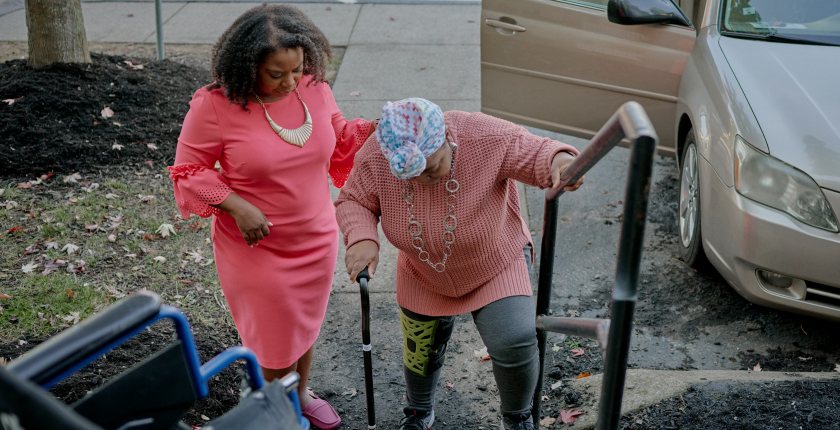 A photo of a woman helping her elderly mother up the stairs.