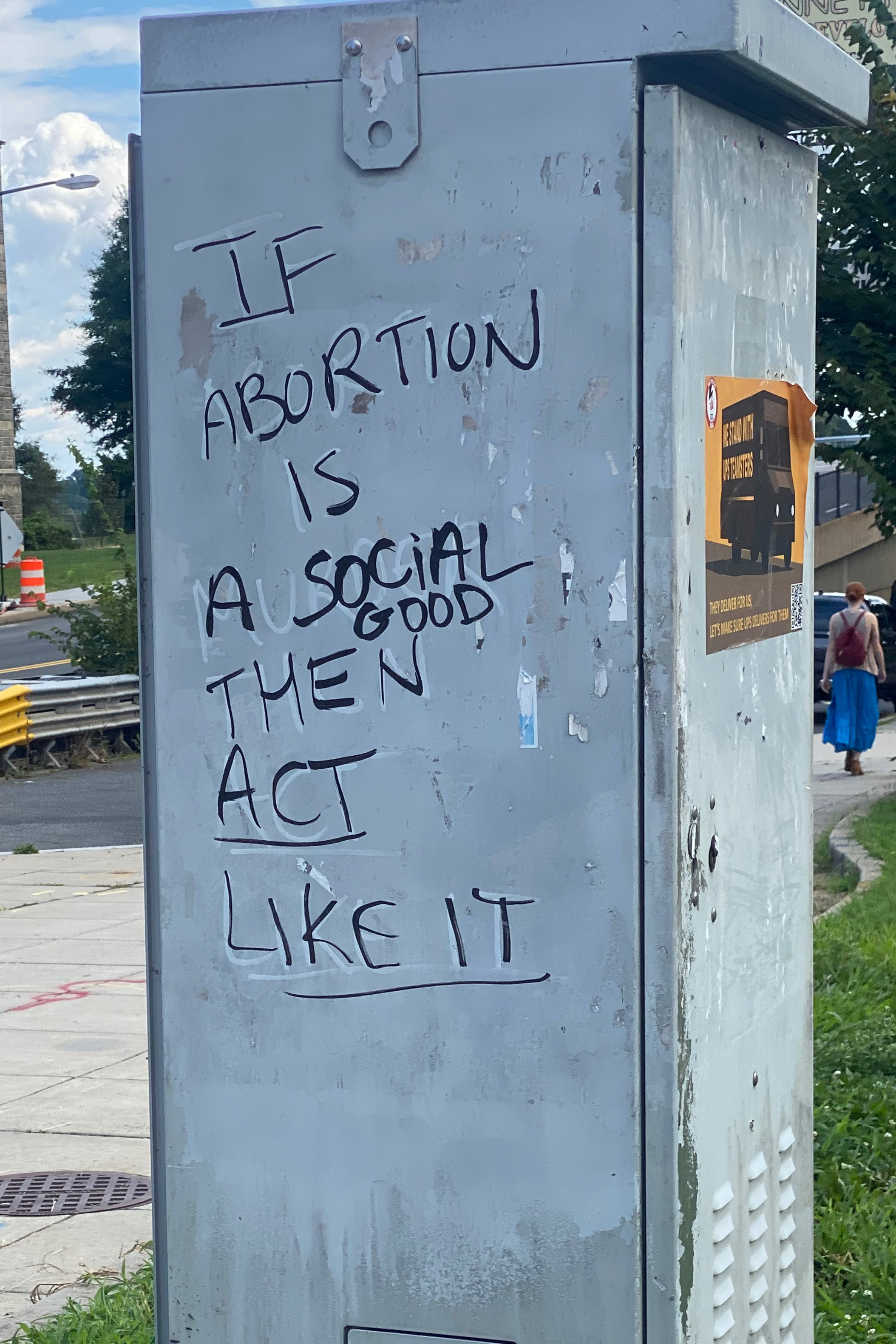 On the side of a metal pillar, graffiti is loosely written in black marker. It says, "if abortion is a social good, then act like it." The black marker has written over white marker, which faintly reads, "abortion is murder."