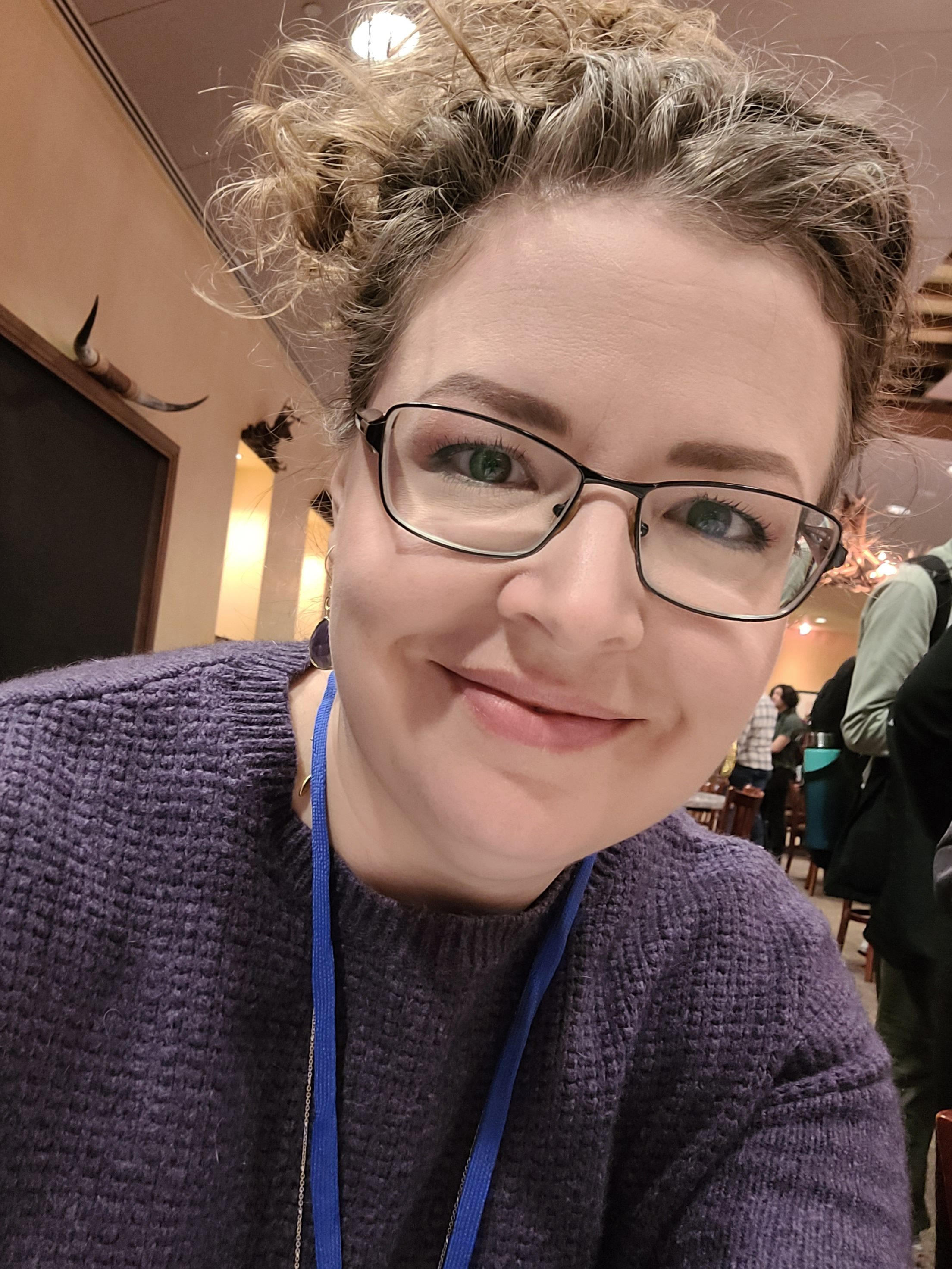 Beth VanOrden, wearing glasses and a purple sweater, smiles at the camera in this selfie-style photograph.
