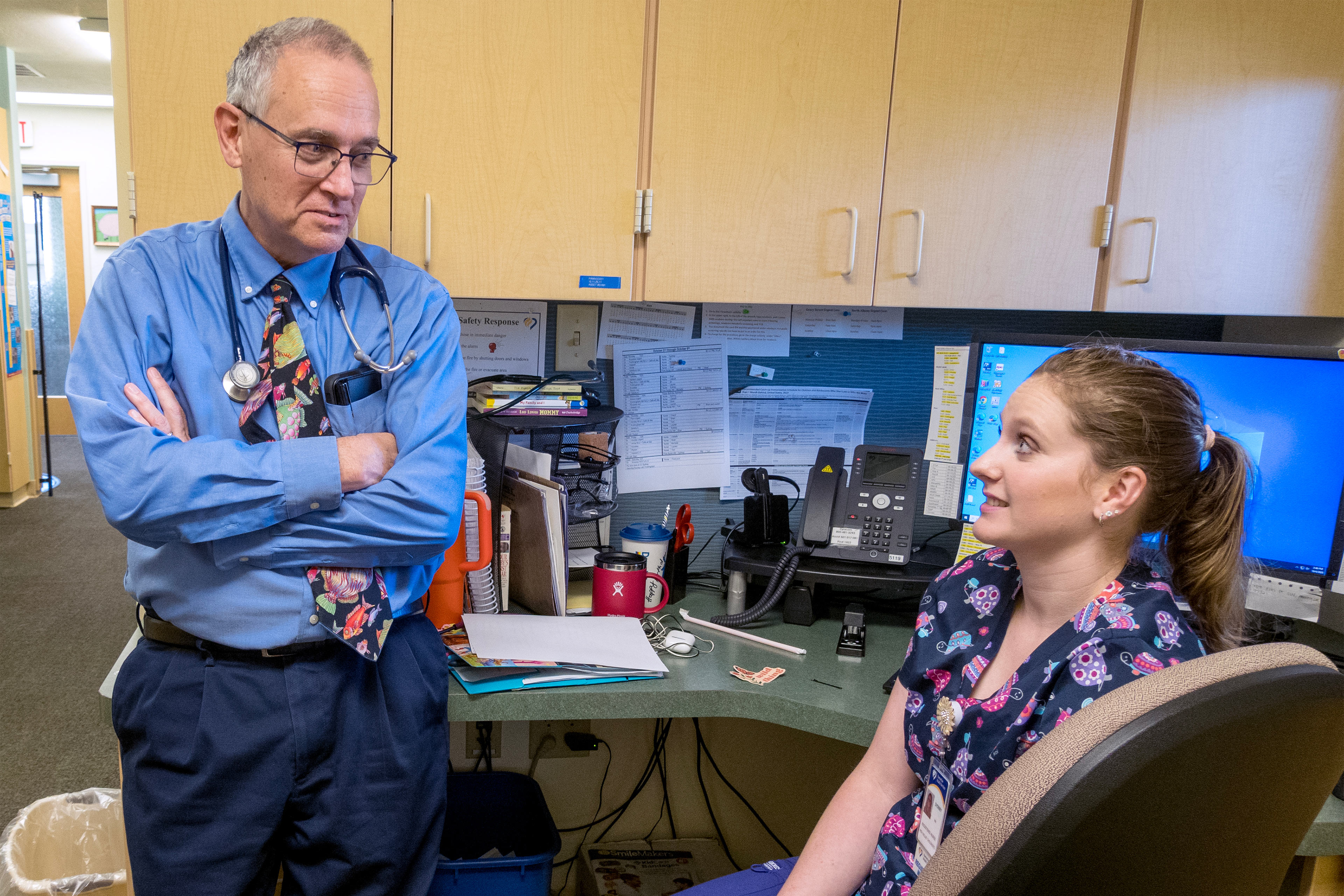 A photo of a doctor talking to a nurse inside of a clinic.