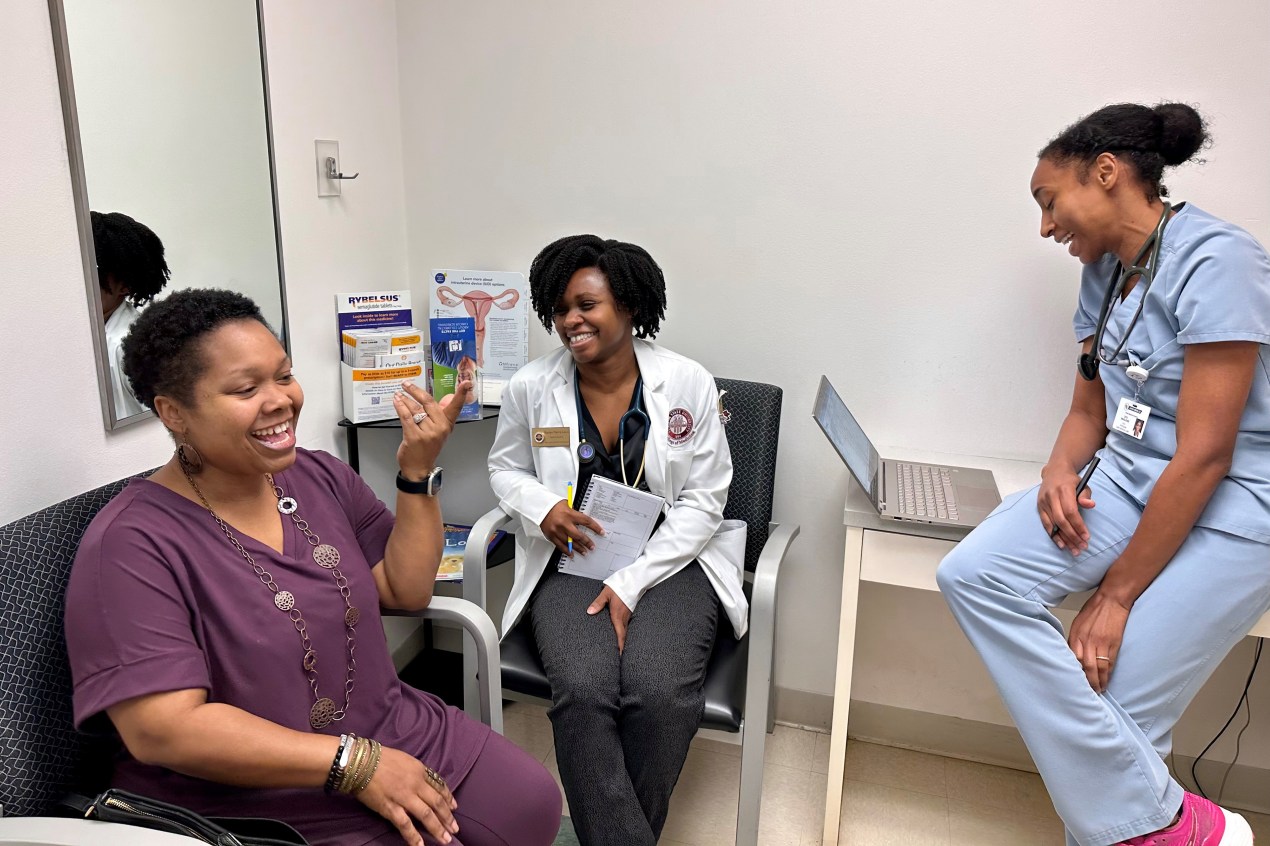 YaSheka Shaw, a patient, sits to the left of medical student Kaniya Pierre Louis (center) and physician Zita Magloire (right).