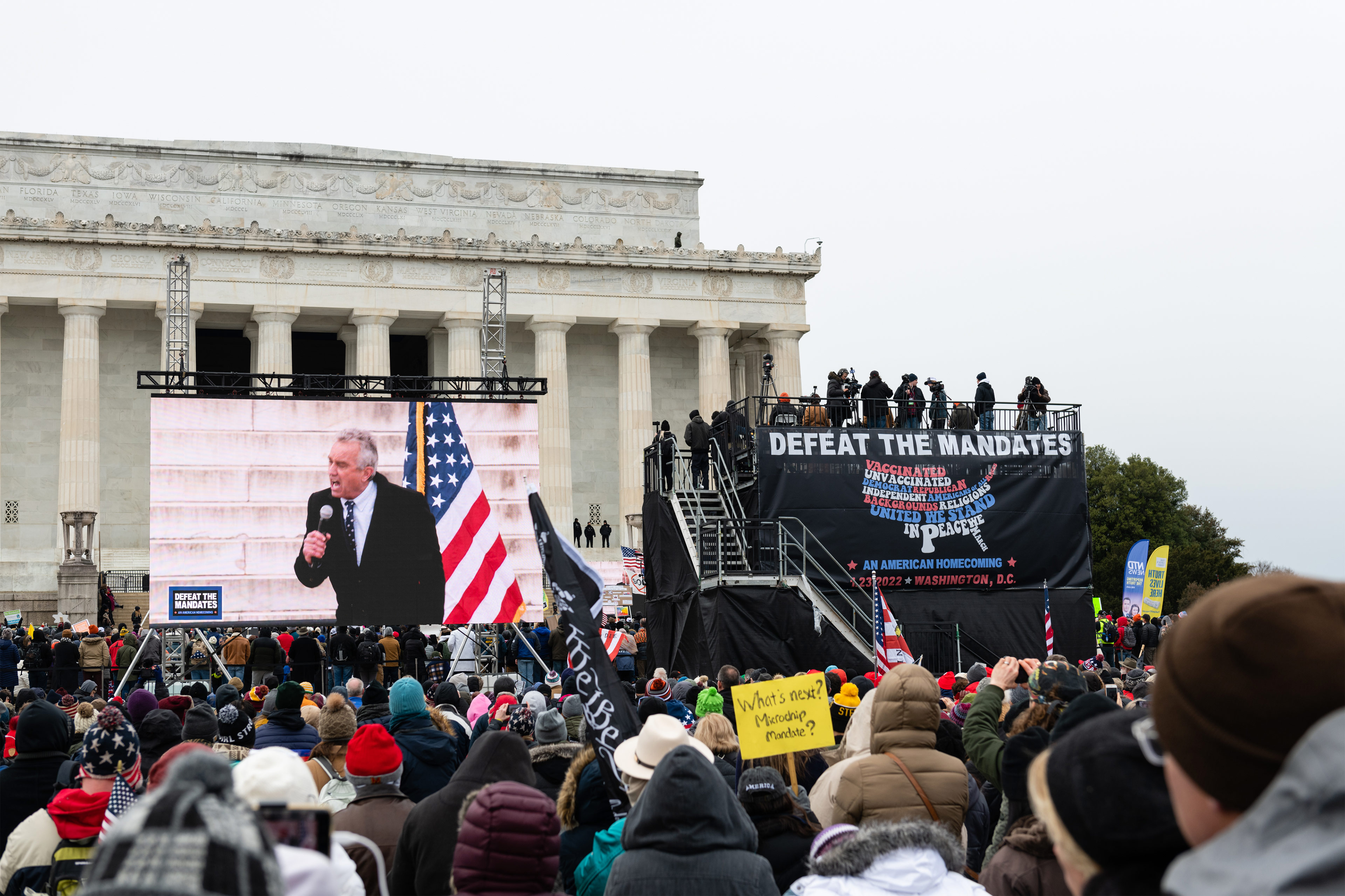 A photo of a crowd of protesters at the Lincoln Memorial in Washington watching Robert F. Kennedy Jr. speak on a screen.
