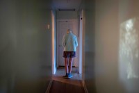 A photo of an elderly woman walking down a hallway indoors.