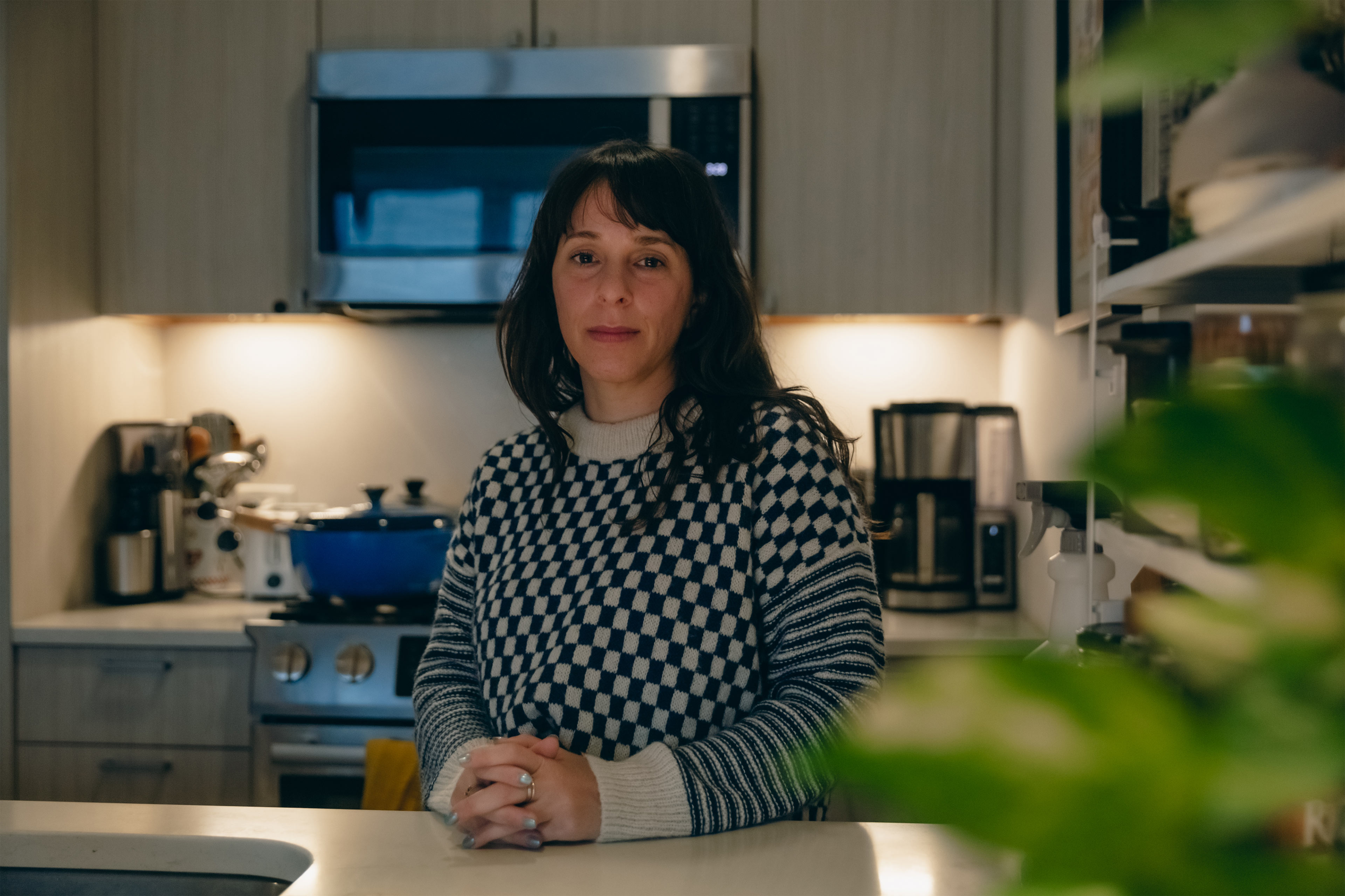 A portrait of a woman indoors in her kitchen.