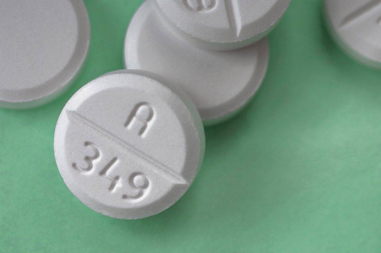 A photo of five Oxycodone pills against a green backdrop.