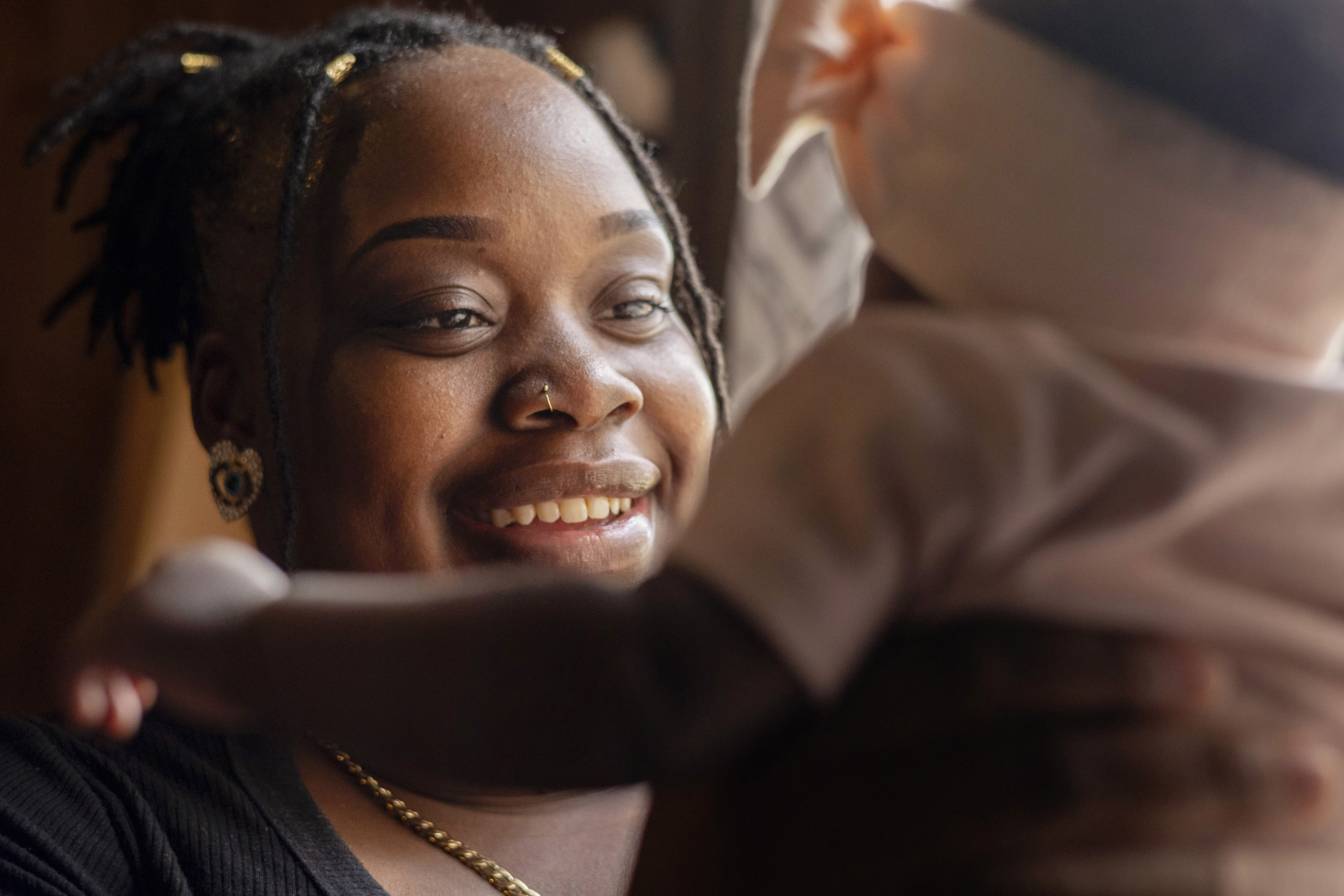 O’laysha Davis holds up her infant daughter. The photograph is framed so that you see O'Layasha smiling at her child, while the baby's back is to the camera.