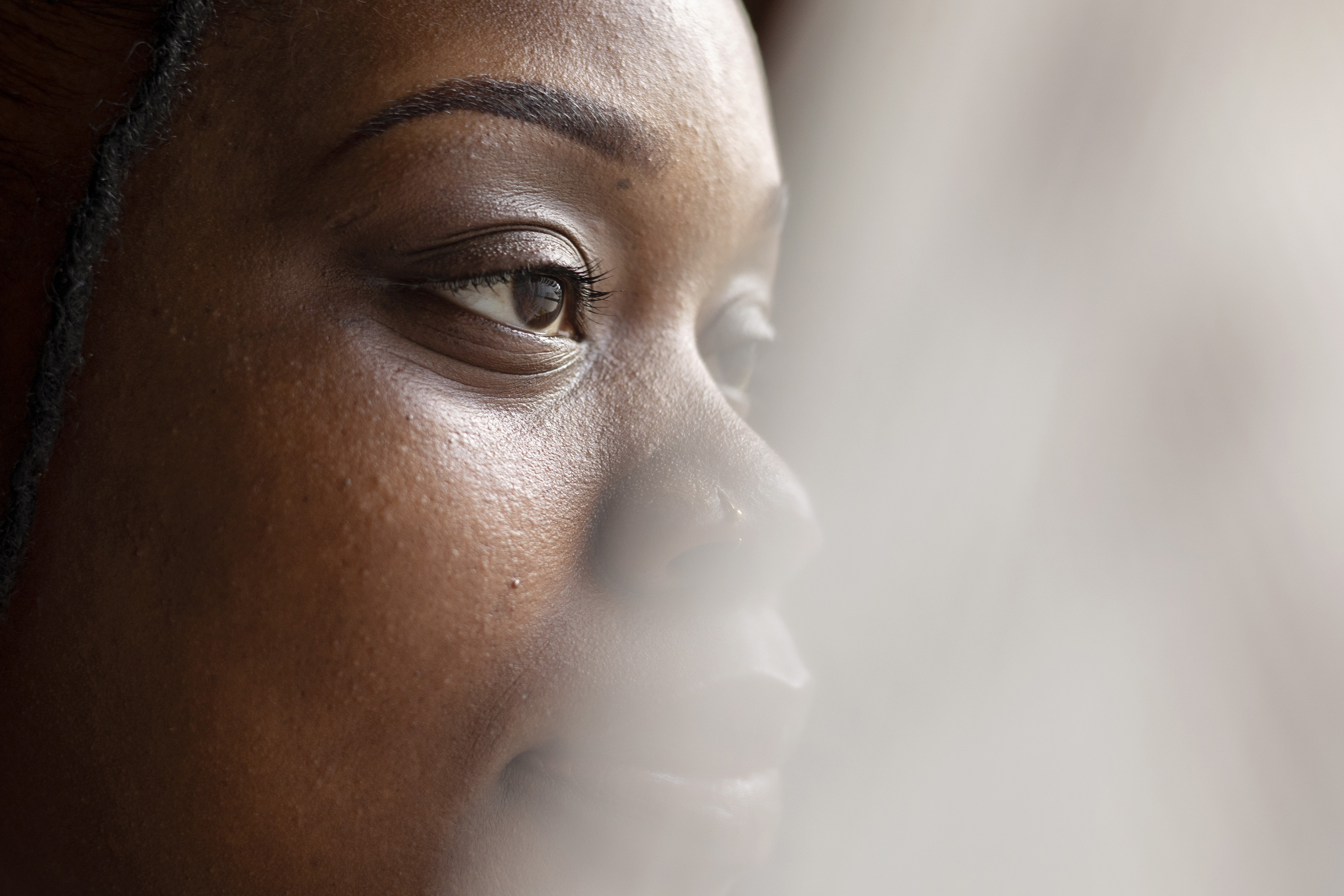 A close-up portrait of O'laysha Davis. Her face is slightly obstructed from view by a sheer curtain.