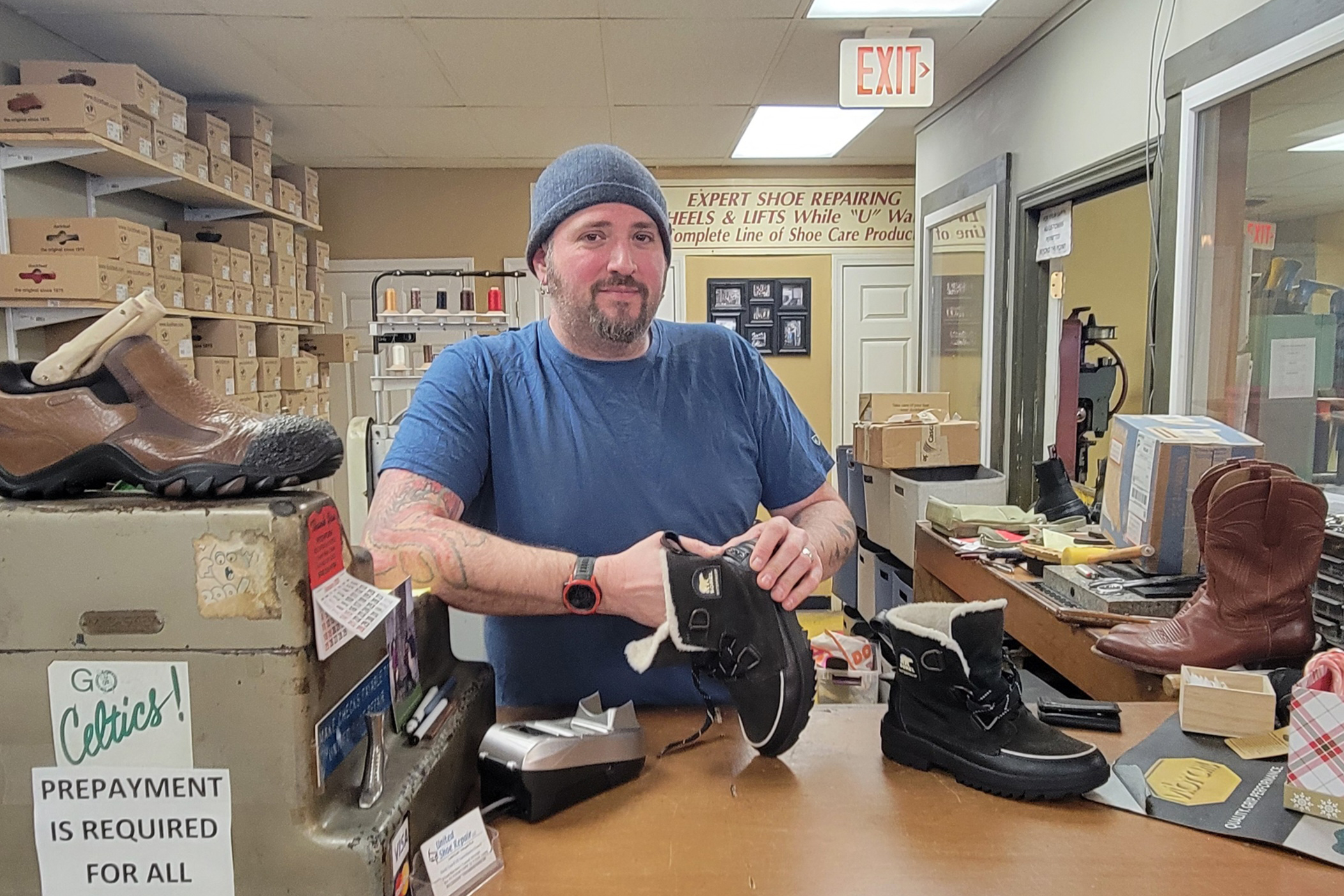 healthy living A man wearing a beanie holds a pair of shoes inside a shoe repair store