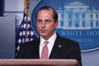 A photo of Alex Azar speaking at a podium to reporters at a press conference.