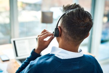 A photo of a call center worker speaking into a headset while at a computer.