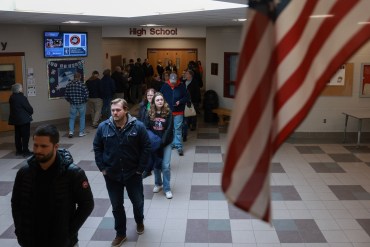 A photo of voters waiting in line to cast ballots indoors.