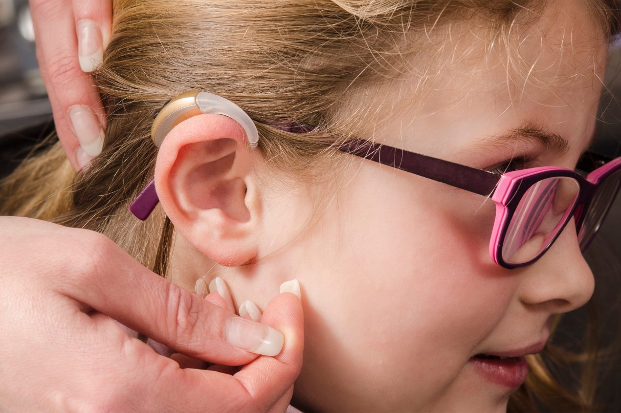 A photo of a person calibrating the hearing aid on a young girl.