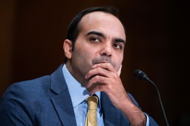 A photograph of Rohit Chopra during the senate hearing. He holds his chin in his left hand in a contemplative position.