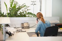 A photo of a female hospital receptionist talking on the phone. She is facing away from the camera.