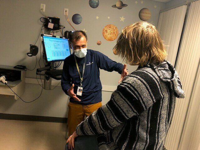 A photo of a pediatrician speaking to a seated child patient.