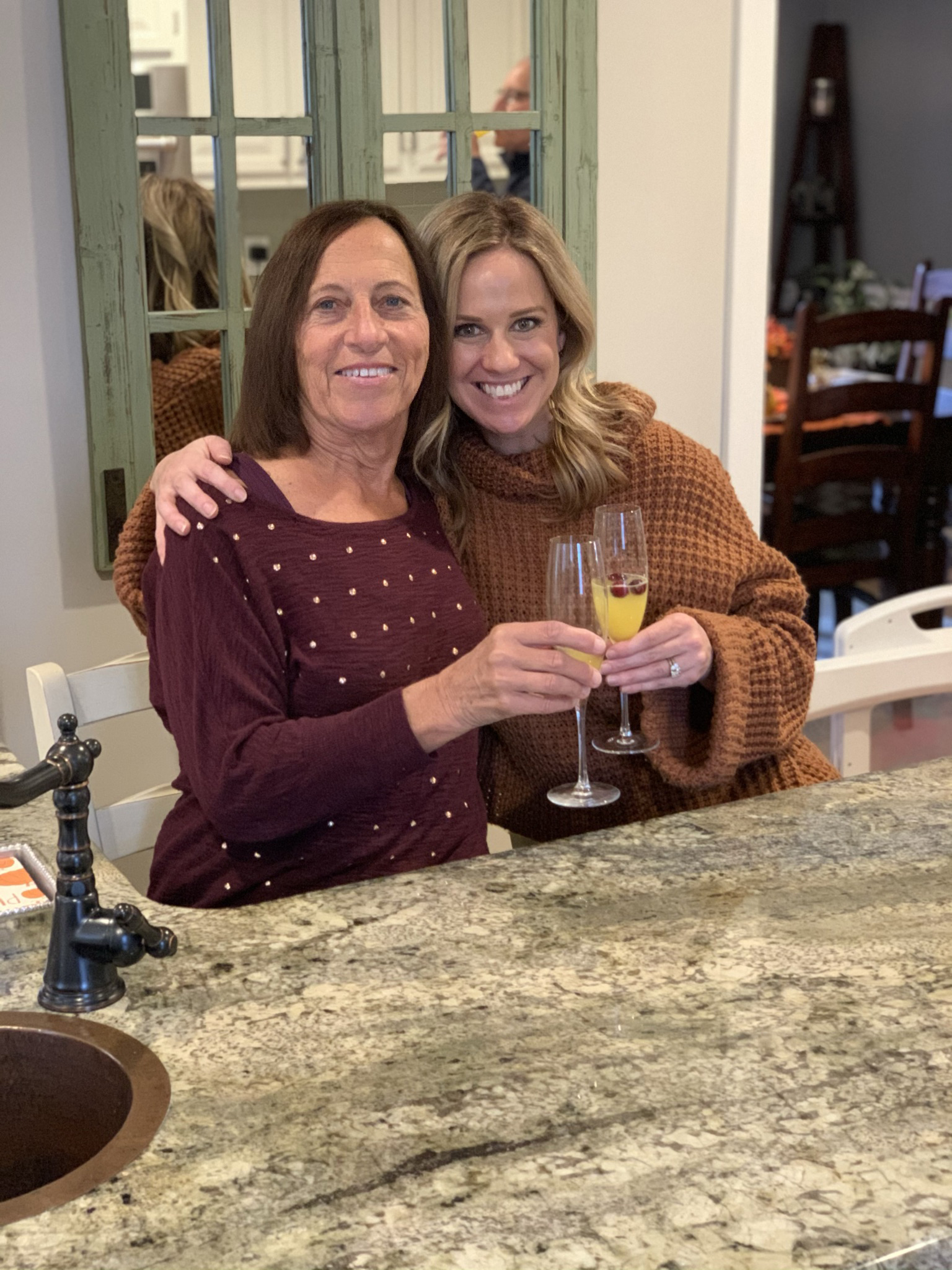 Carol Rosen (à esquerda) e sua filha, Lindsay Murray (à direita), estão em sua casa.  Cada um deles segura uma taça do tamanho de champanhe e um brinde.