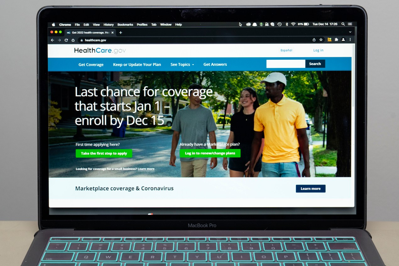 A photograph of a laptop. On the screen is the homepage for healthcare.gov.
