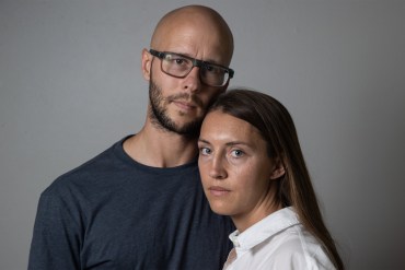 A photo of a mother and father posing for a portrait indoors.