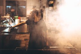 A photo of a man working in a steamy restaurant kitchen.