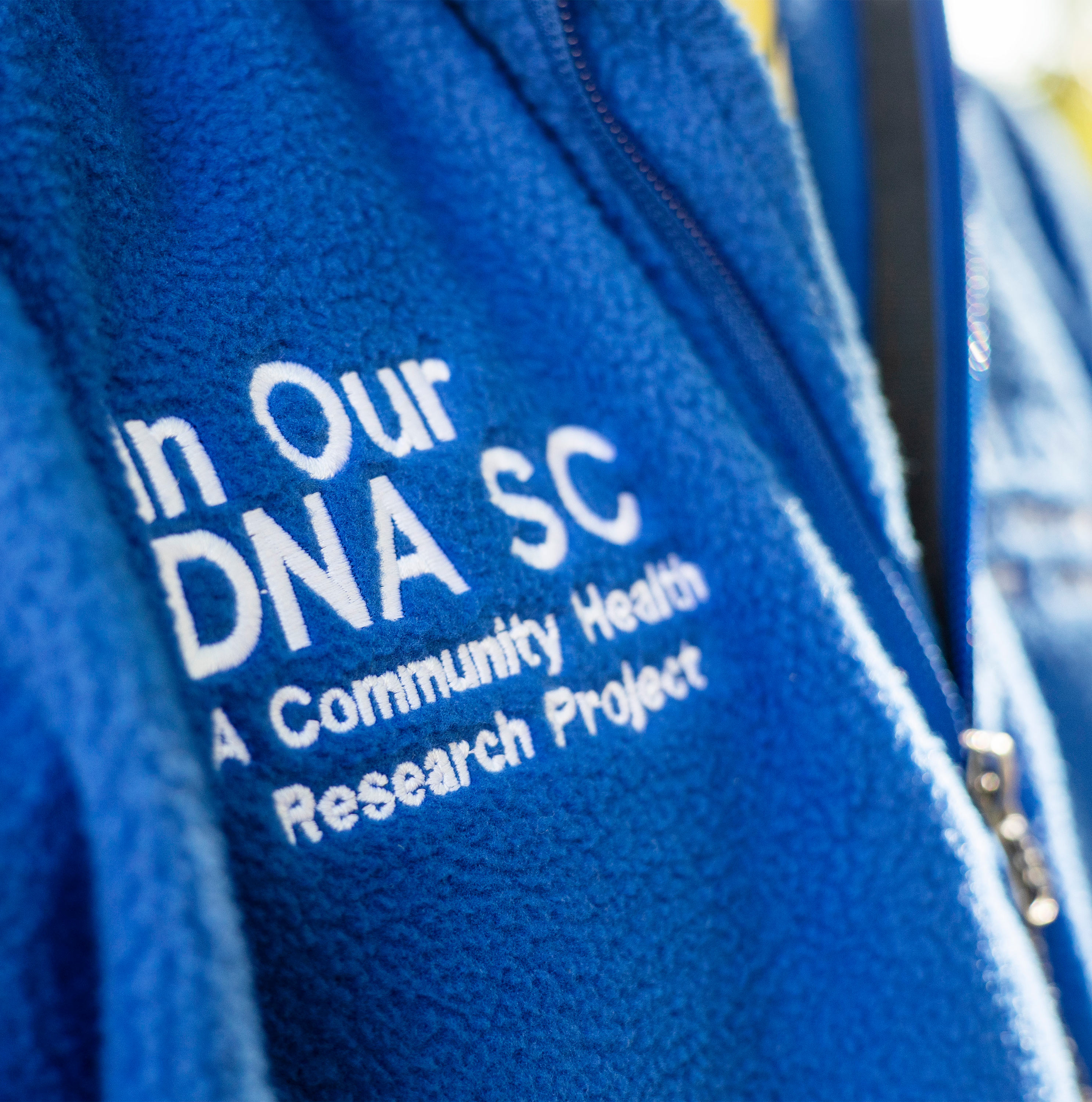 یک نمای نزدیک کلمات را نشان می دهد، "در ما DNA SC" روی پیراهن کش آبی لی مولتری نوشته شده است.