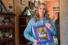 Marianne Sinisi stands in her home and holds a framed photograph of her son.