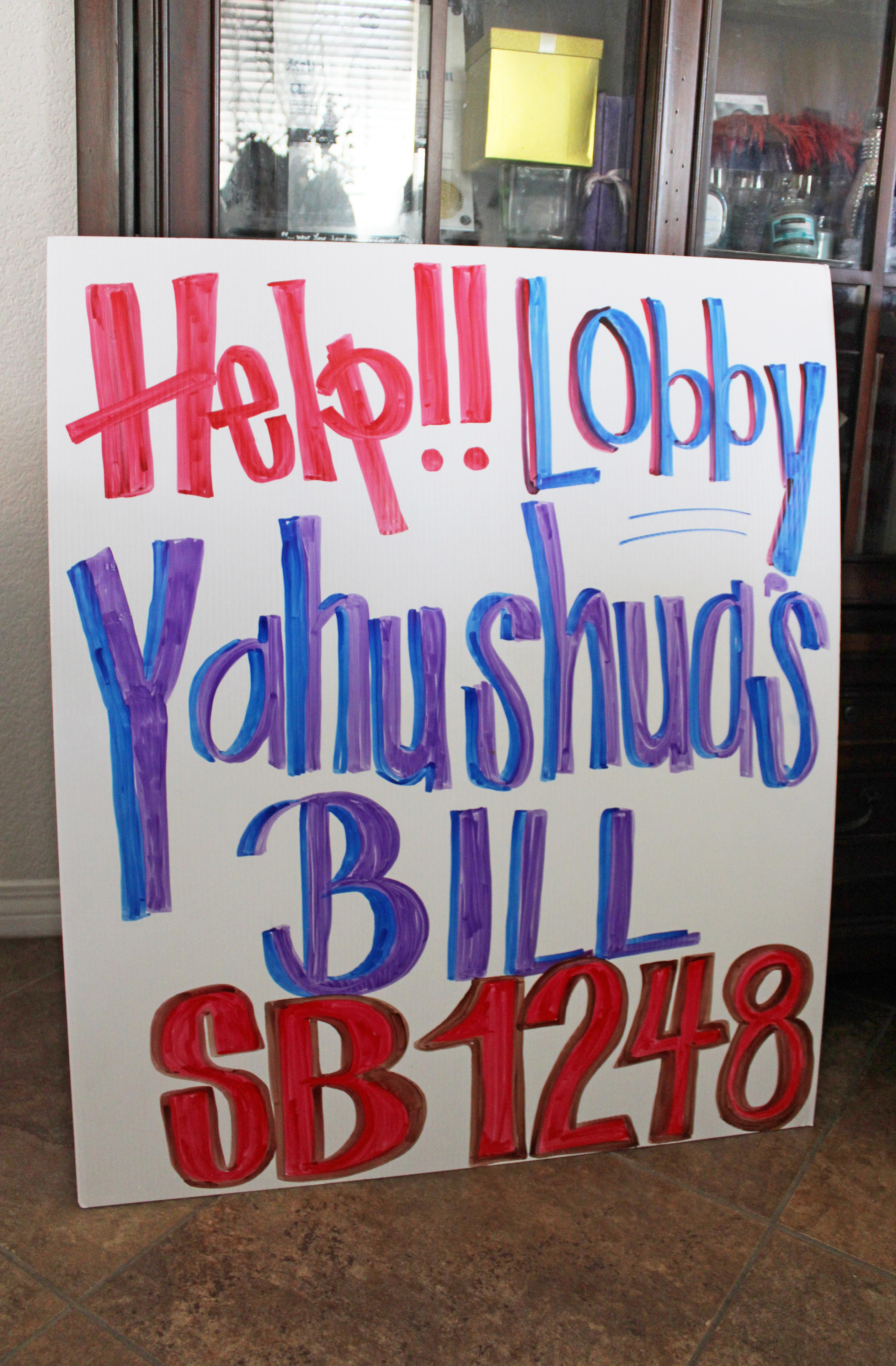 A hand-drawn sign, that is poster-size, reads, "Help!! Lobby Yahushua's Bill SB1248."