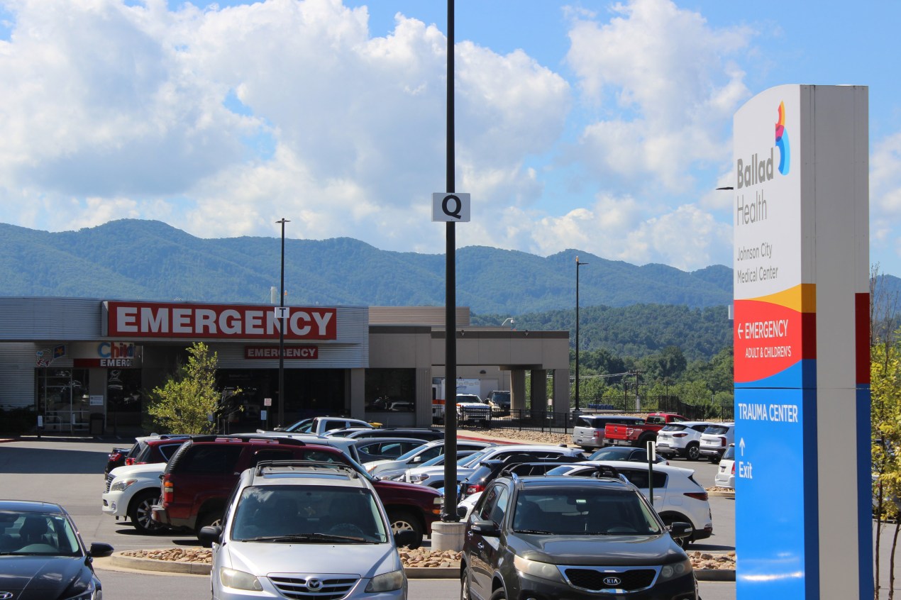 A photo of a hospital parking lot and emergency room entrance.