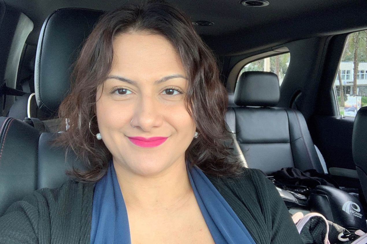 A photo of a woman sitting inside a car and smiling.