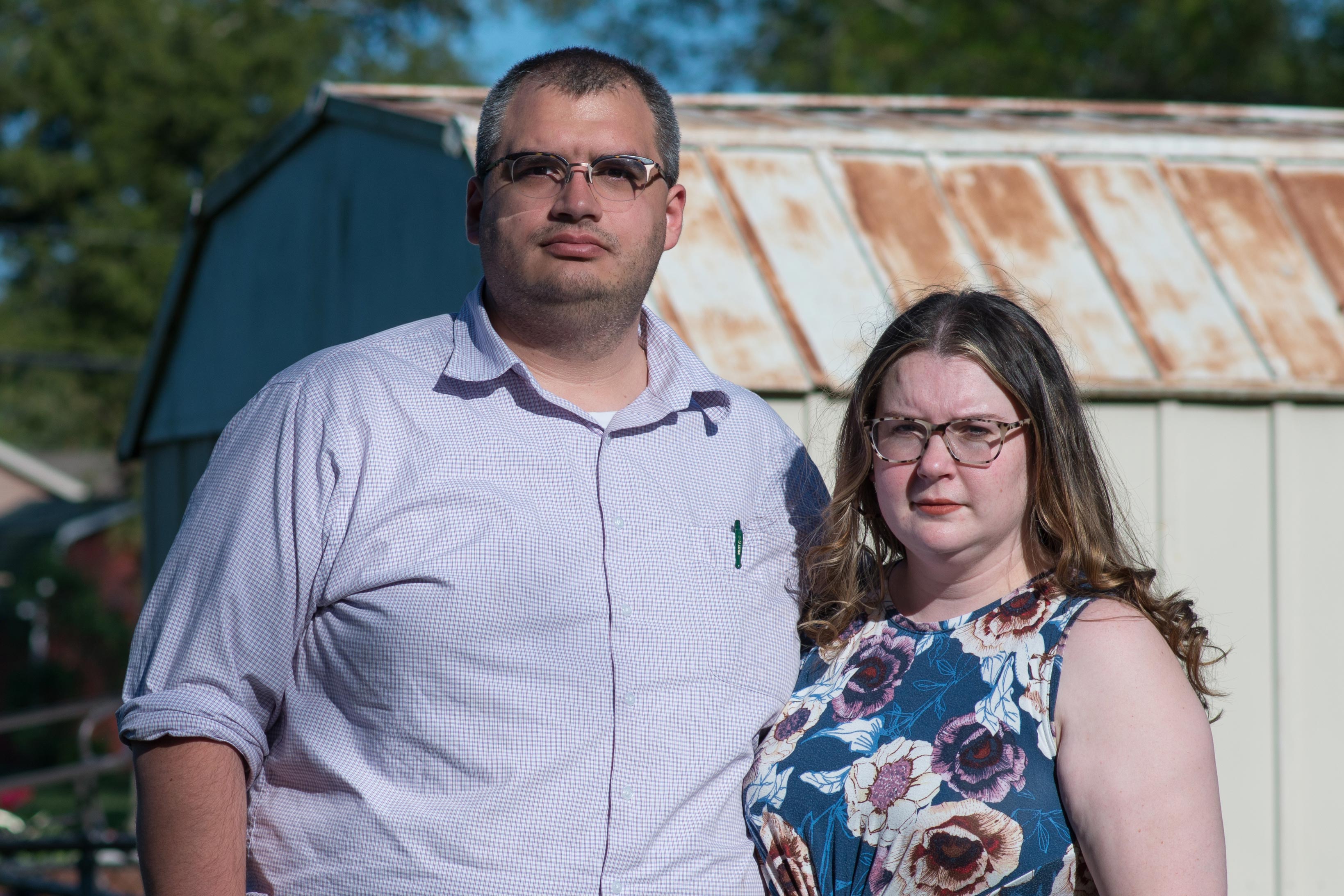 A portrait of a father and mother standing outside.