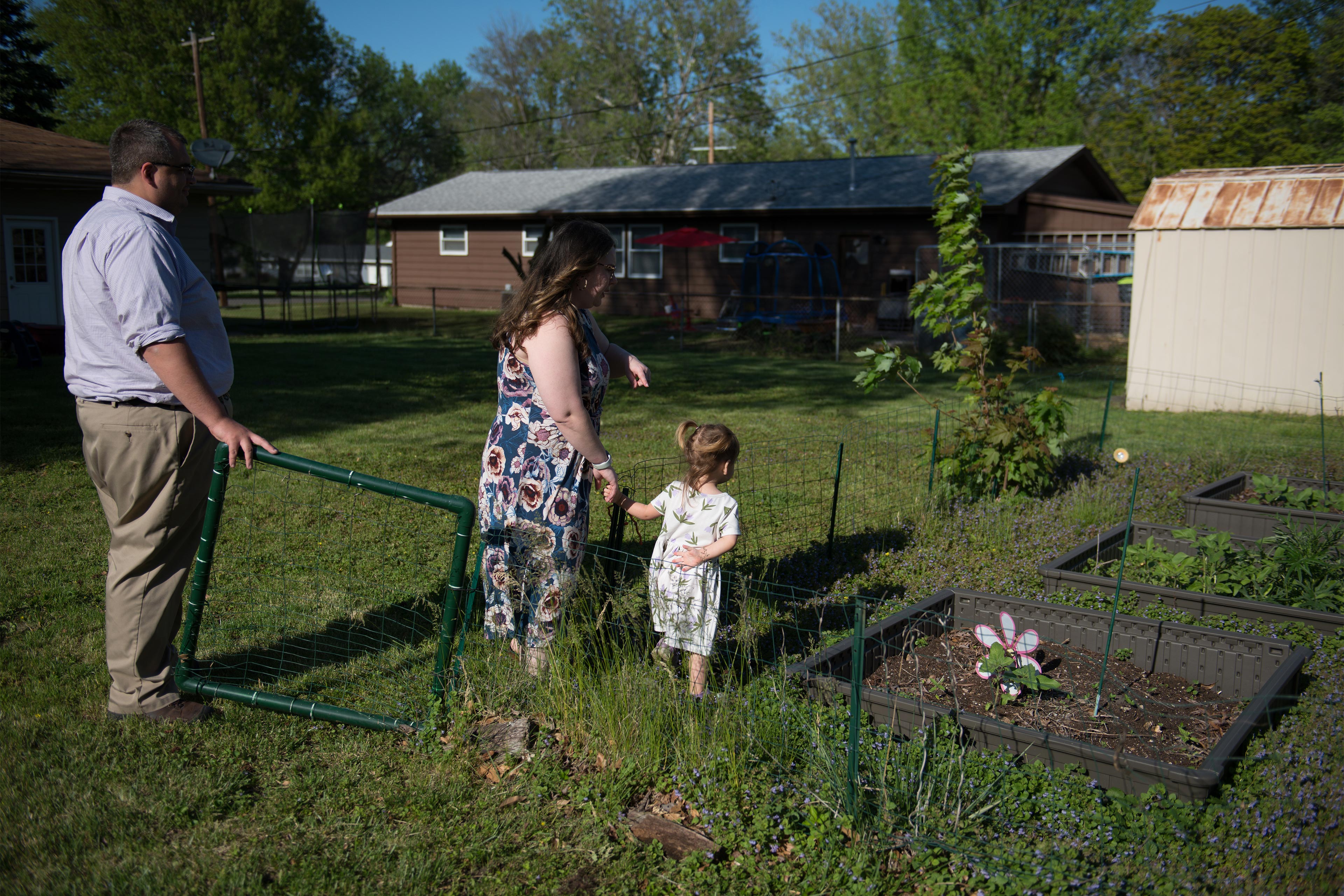 Business A photo of two parents showing their toddler daughter a garden in their yard.