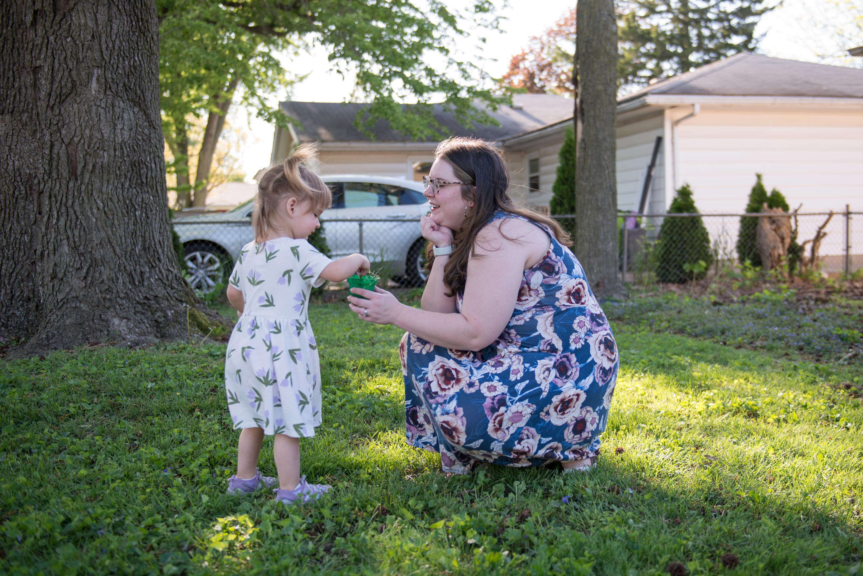 Business A photo of a mother showing a small planter to her daughter outside.