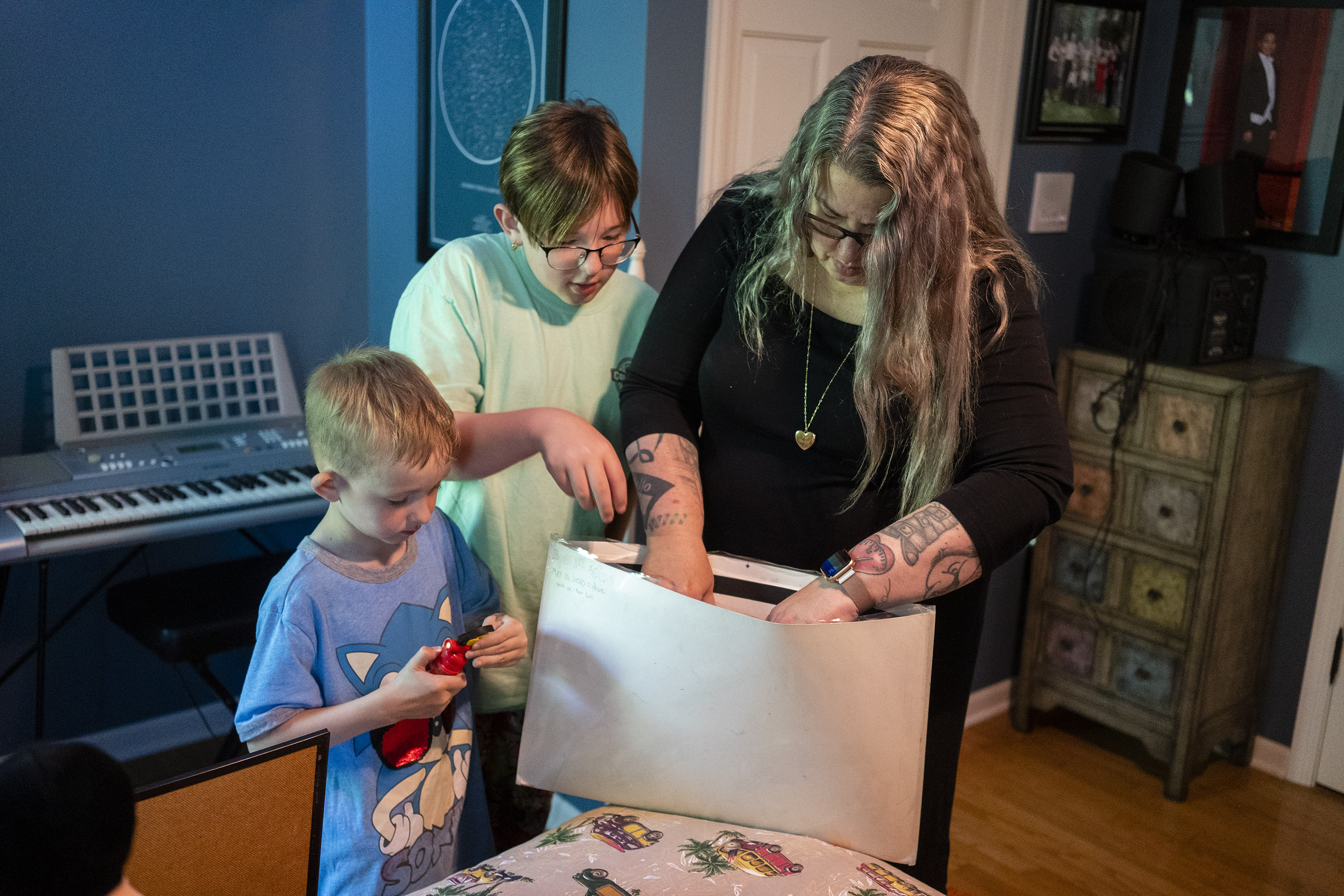 A photo of a mom and two sons looking in a folder in a bedroom.