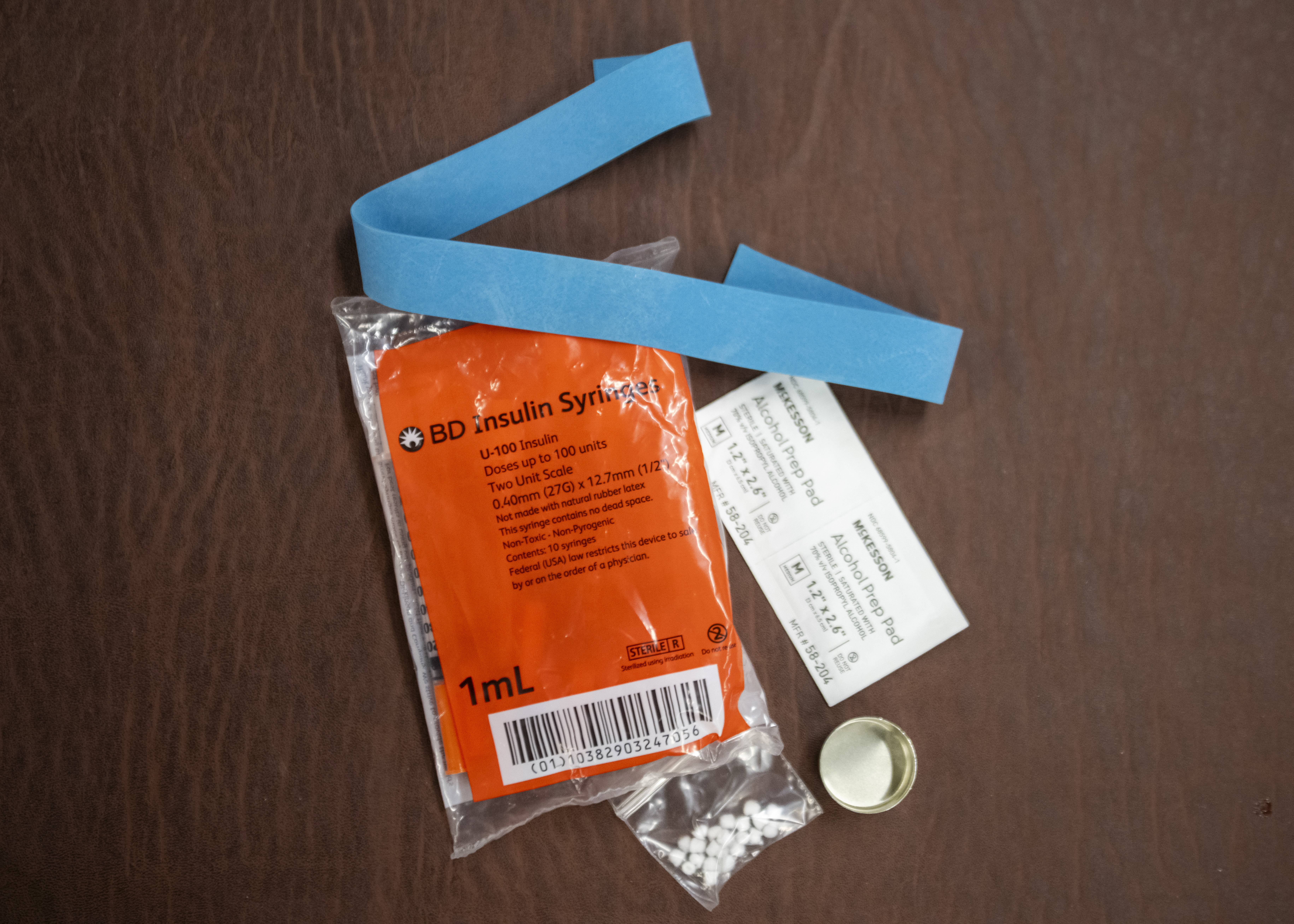 A close up of a clean syringe kit wrapped in plastic with an orange label